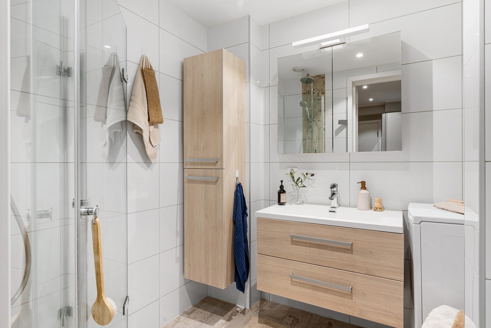 Pent innredet bad med dusj, baderomsinnrednng med servant, overskap med speilfront og belysning Galleribilde