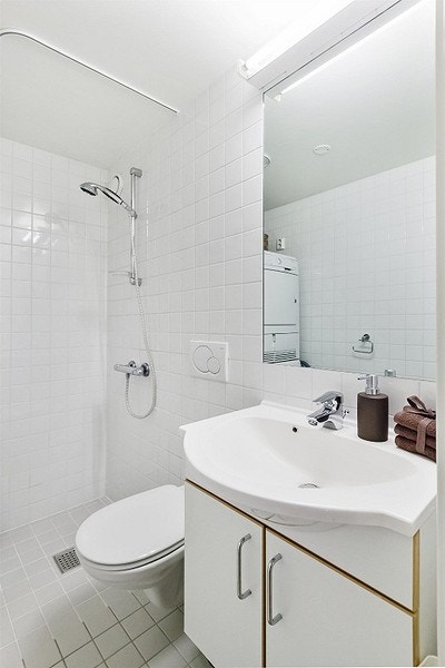 Badet er innredet med dusjhjørne, vegghengt toalett, servant med underskap og speil over vask. Galleribilde