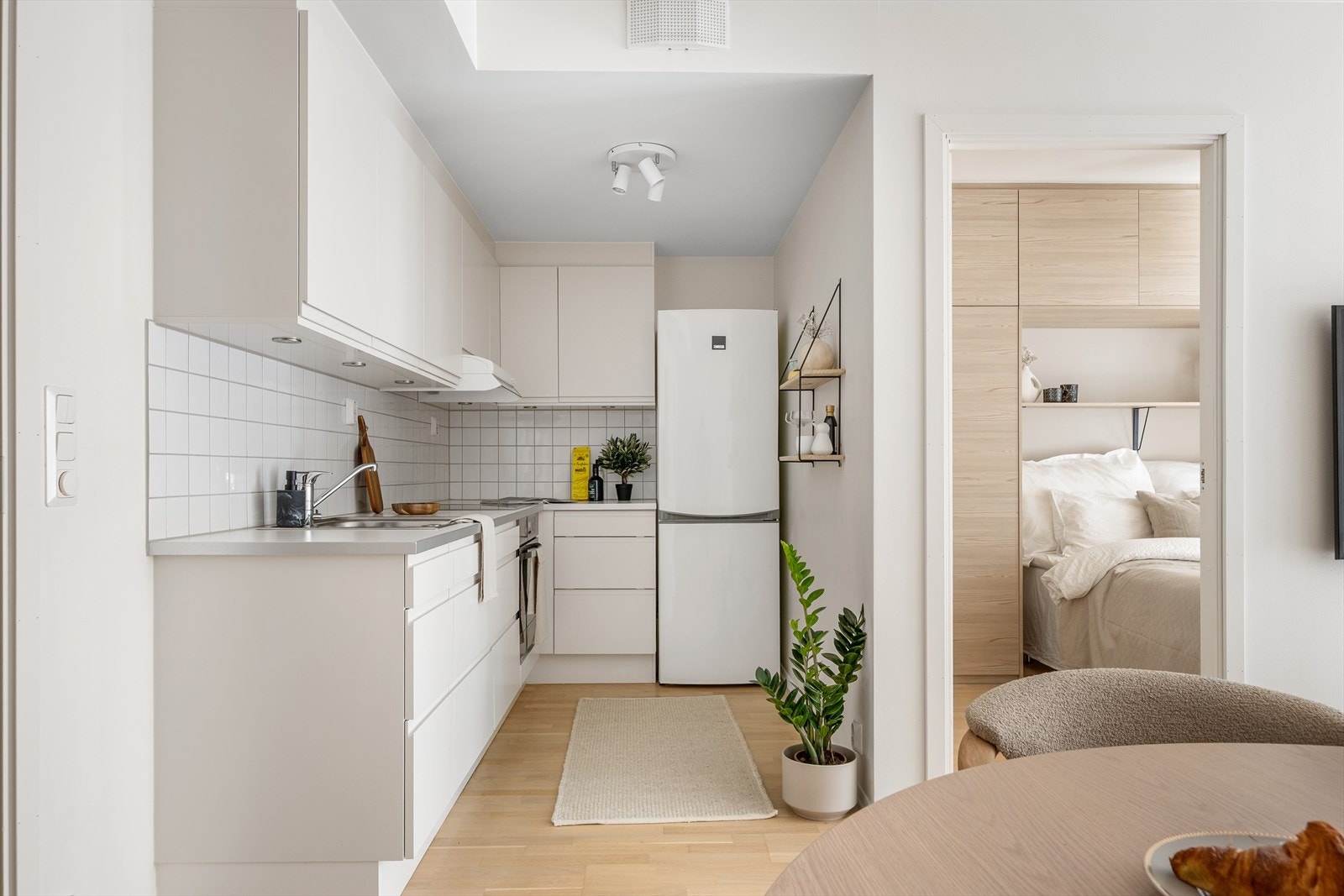 Stilrent kjøkken med kjøkkeninnredningen bestående av hvite, glatte fronter og benkeplate av laminat med nedfelt vask- og skyllekum. Galleribilde