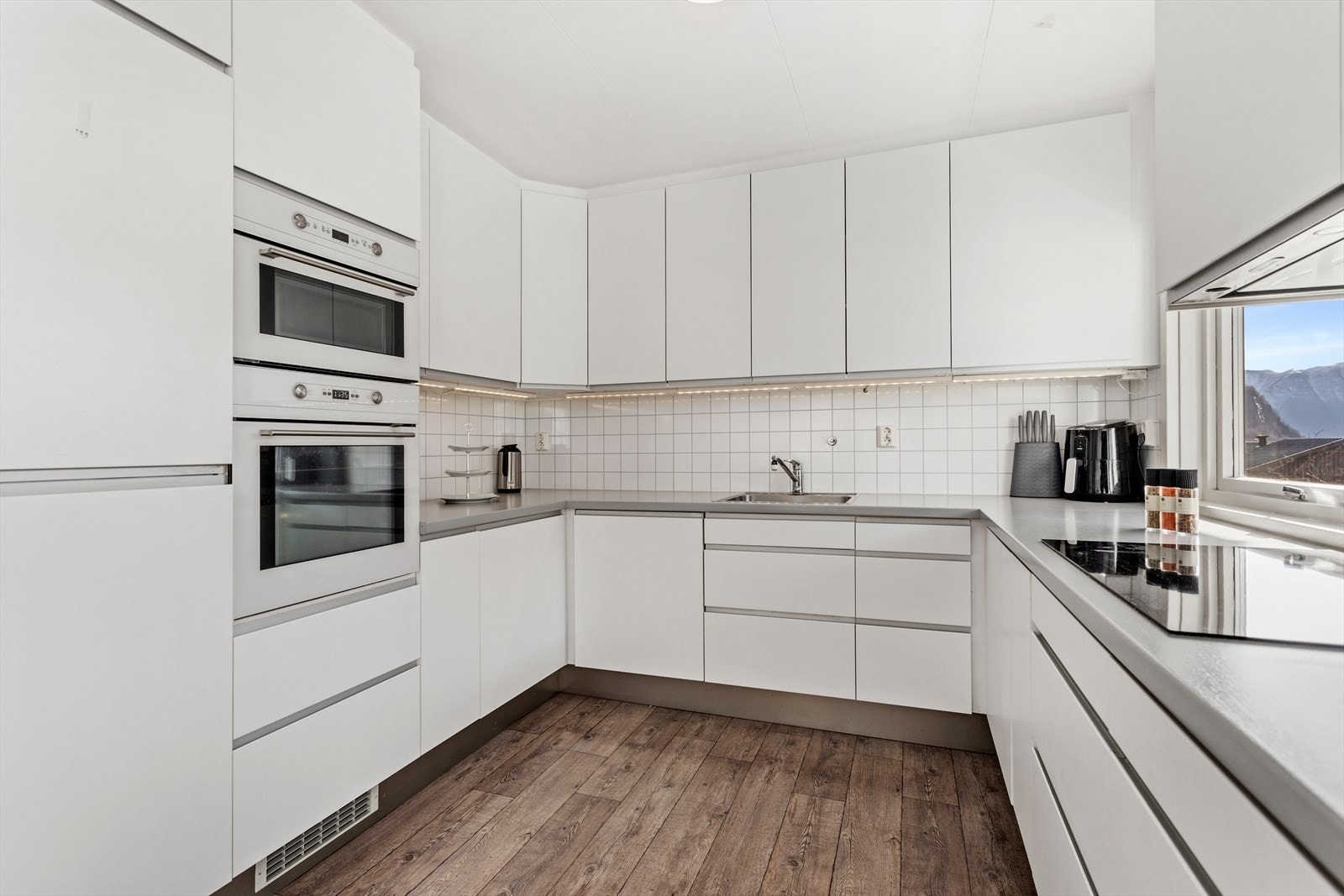 Kjøkkendelen har innredning med kvite glatte frontar og benkeplate av laminat. Galleribilde