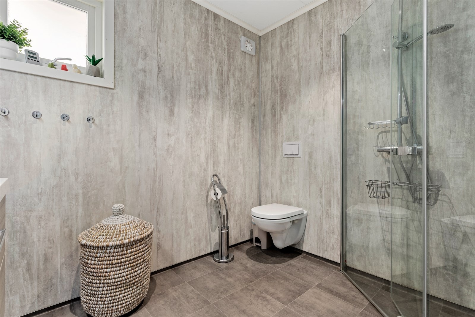 Innreiing består av nedfelt servant med underskuffer, ovreskåp med spegel i front, veggmontert toalett og dusjhjørne med innfellbare glasveggar. Galleribilde