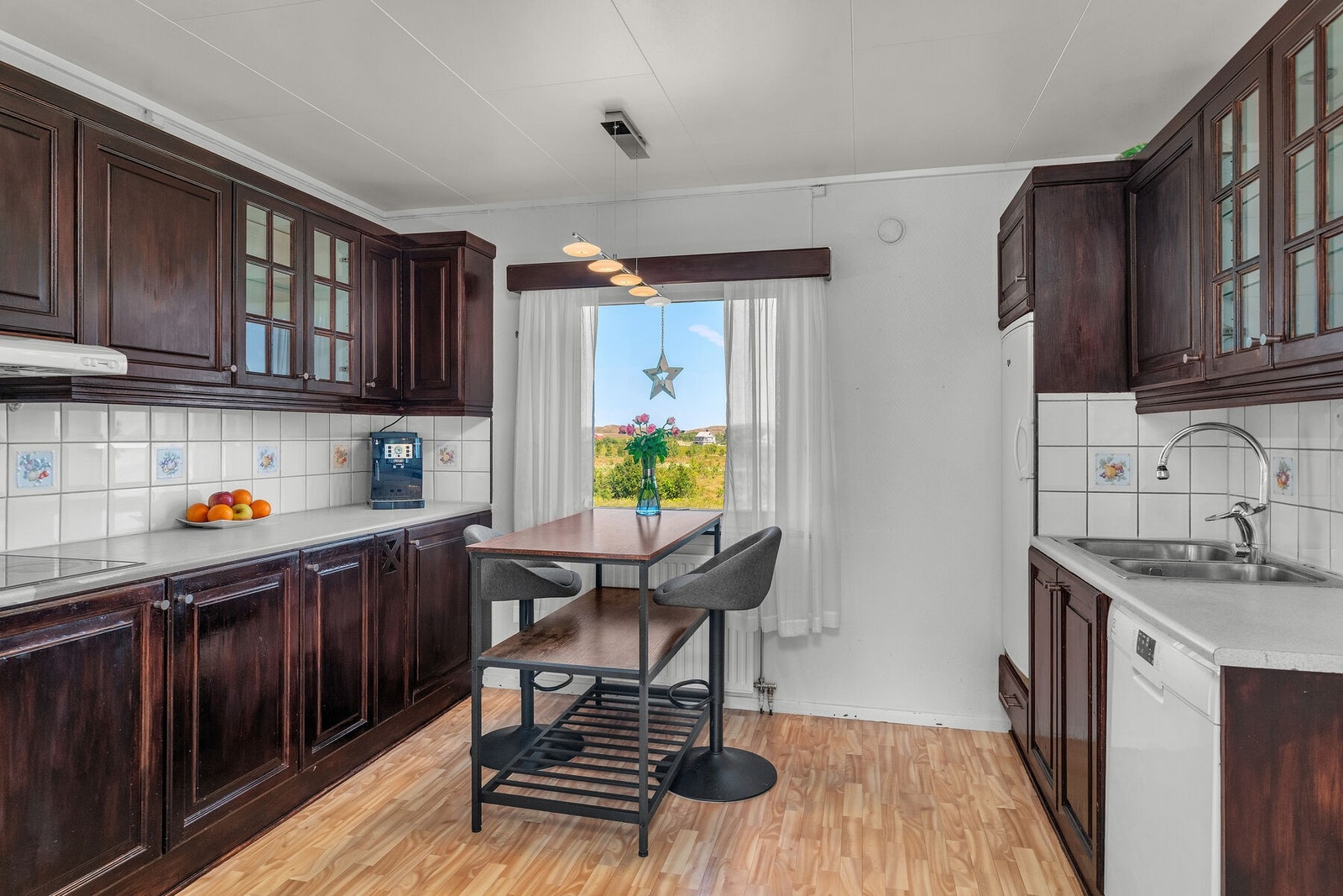 Kjøkkeninnredning med malte, profilerte fronter, benkeplate med kum, over og underskap. Det er integrerte hvitevarer bestående av komfyr og komfyrtopp. Galleribilde