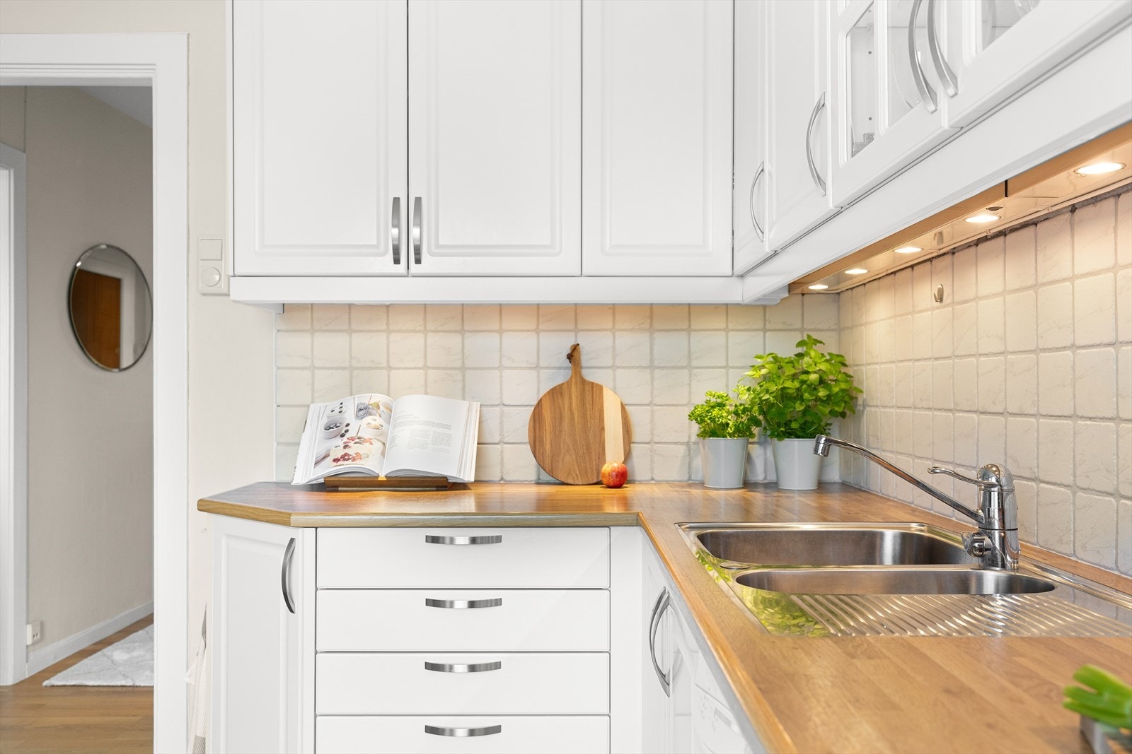 Over kjøkkenbenken er det flislagt vegg og benkebelysning under overskapene. Galleribilde