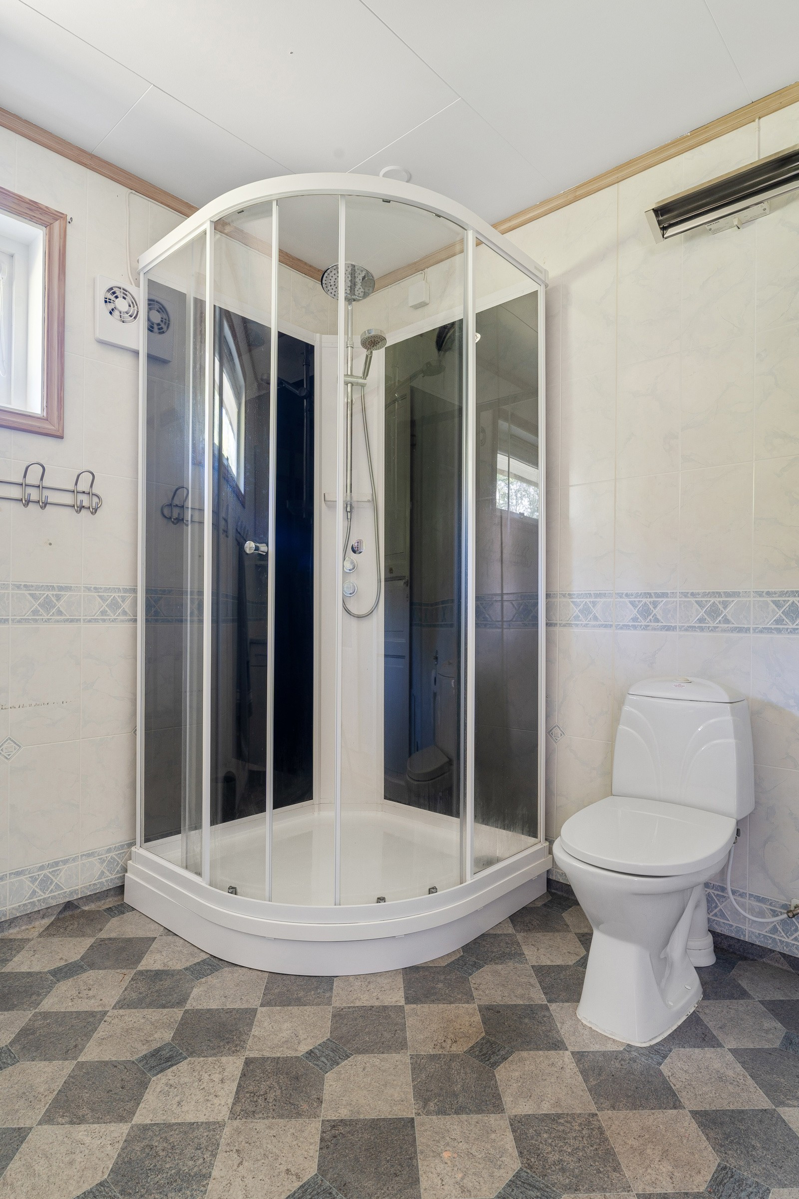 Badet har vindu og stråleovn på vegg. Badet er fra byggeår og har baderomsplater på veggene og våtromsbelegg på gulv.