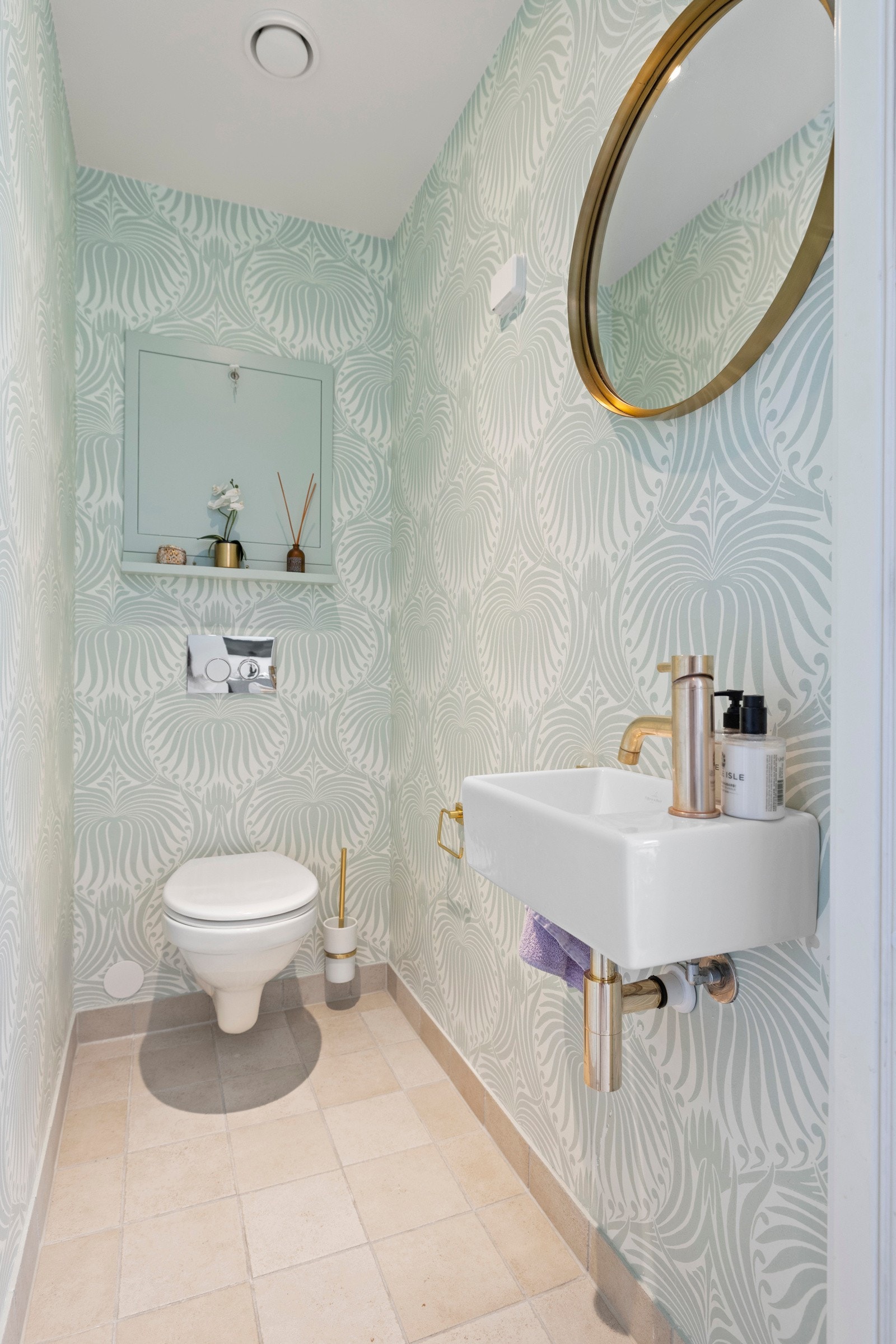 Stilfullt gjestetoalett med moderne detaljer, gullarmatur og elegant tapet - et praktisk og smakfullt tillegg til boligen. Galleribilde