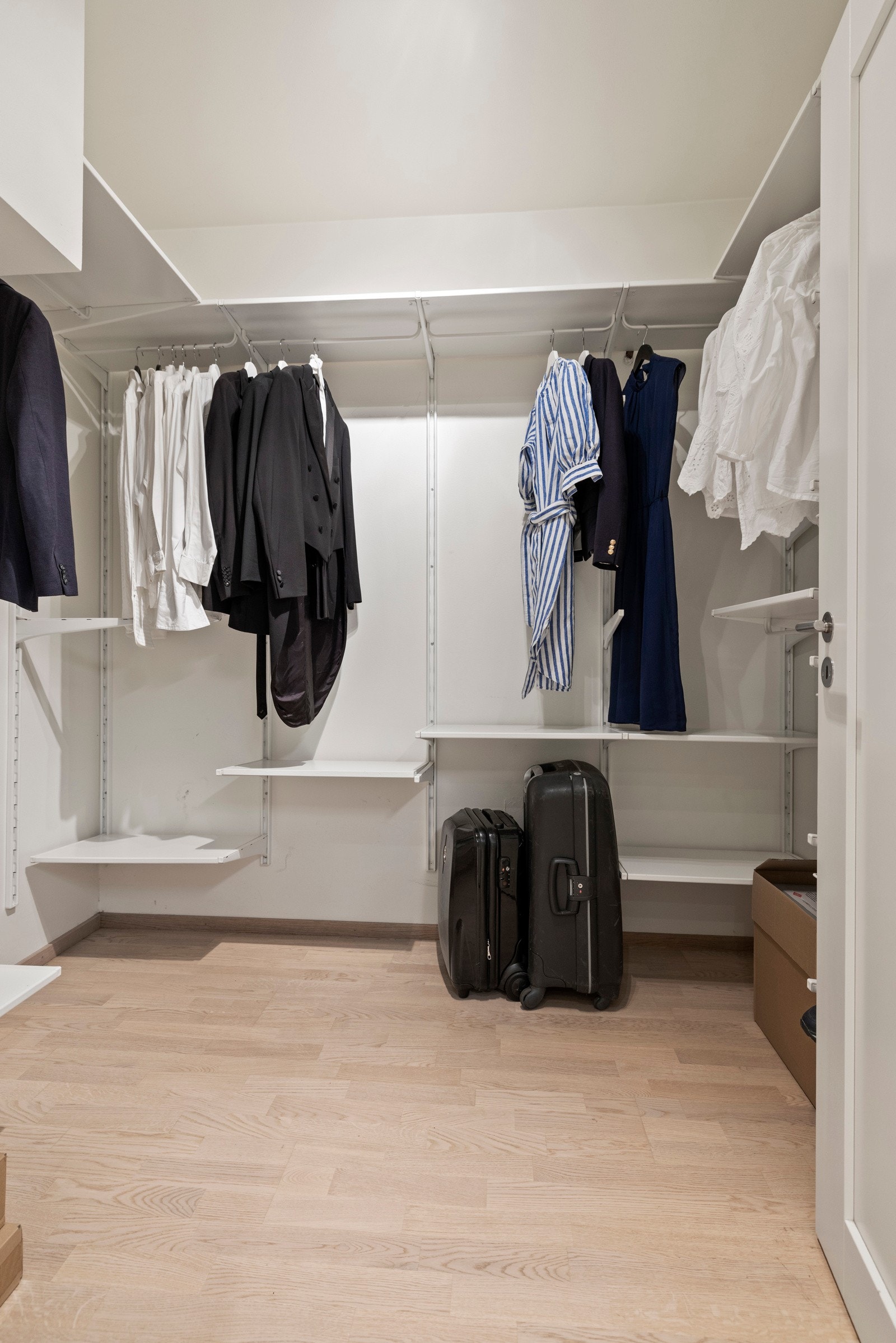 Romslig walk-in closet med skreddersydde oppbevaringsløsninger - stilfullt, organisert og perfekt for enkel tilgang til klær og tilbehør. Galleribilde
