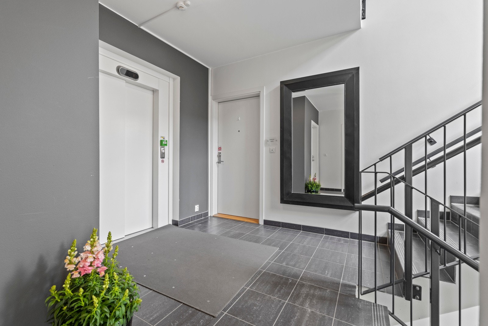 Elegant inngangsparti med heis, speil og stilren trapp. Galleribilde