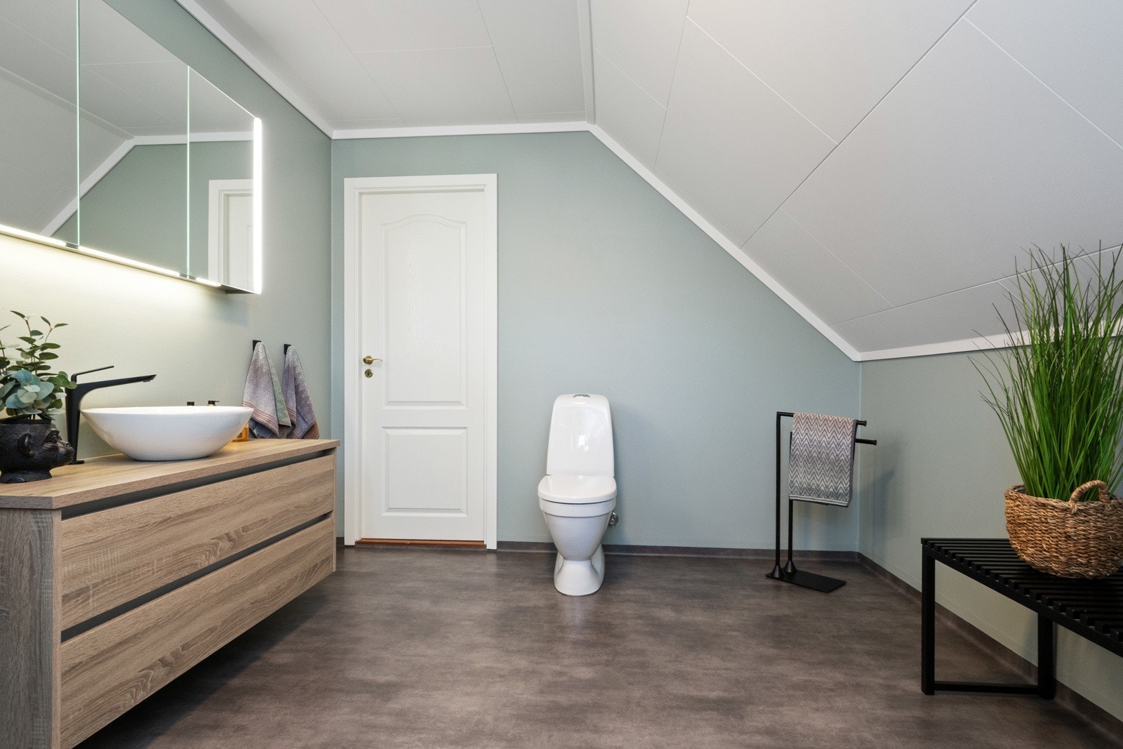 Her får man et romslig og moderne bad, der et dusjhjørne er utstyrt med sort regnfallsdusj og svingbar dør Galleribilde