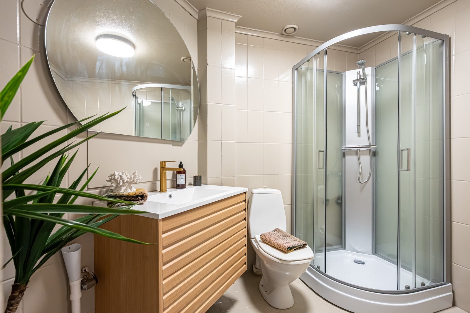 Flislagt baderom med ny servantinnredning, armatur, speil og dusjkabinett i 2025. Galleribilde