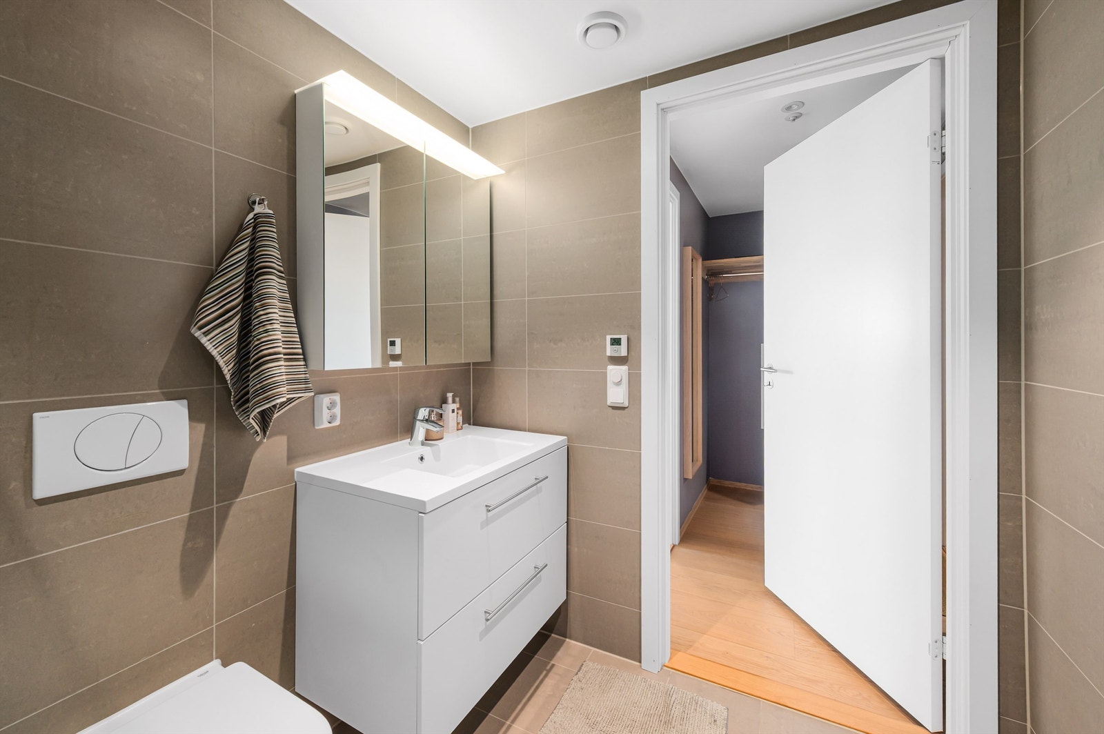 Innredningen består av vegghengt toalett, servant nedfelt i innredning, speilskap m/lys og dusjhjørne med svingbare glassdører. Galleribilde