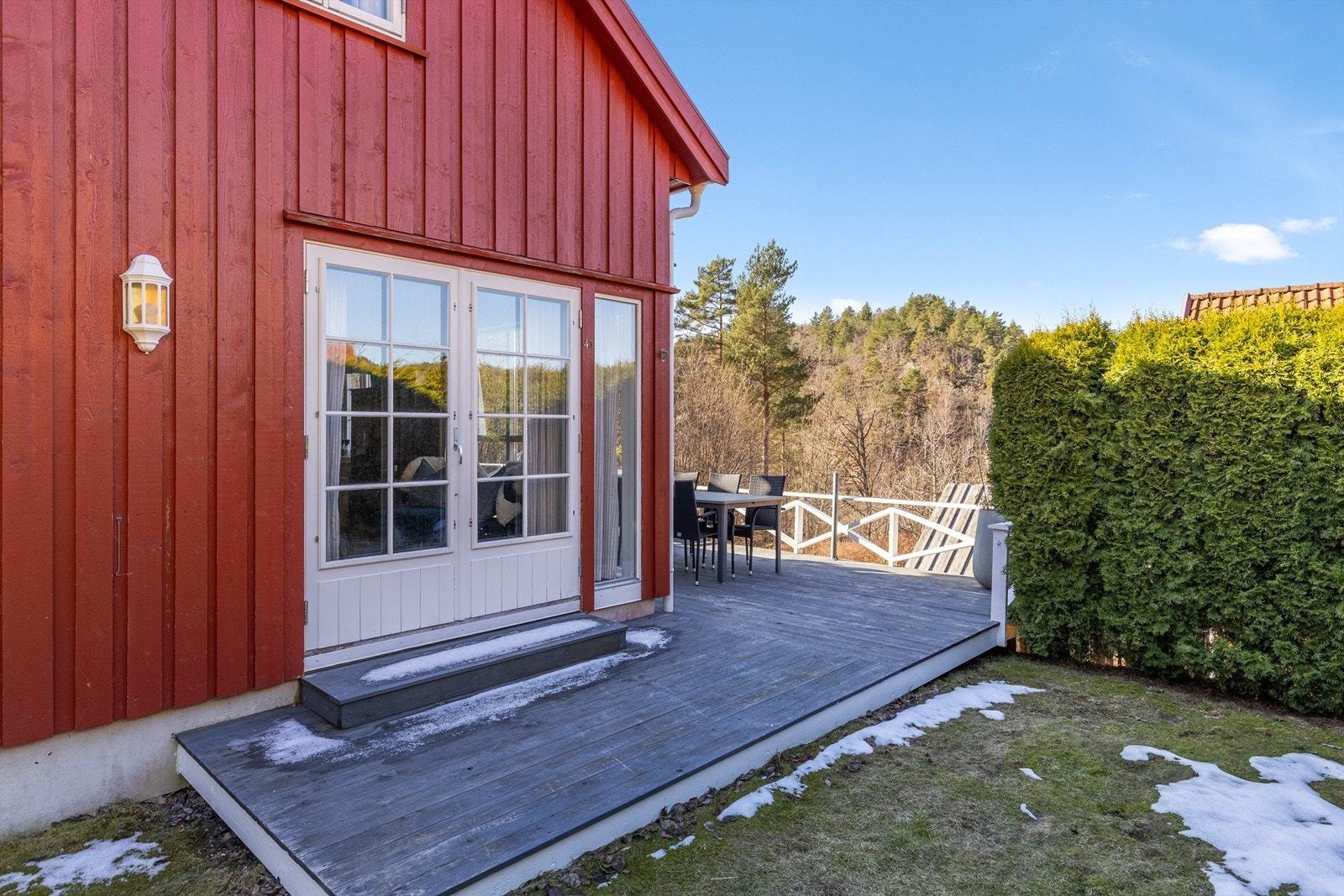 Stor terrasse som går rundt tre sider av hytta Galleribilde