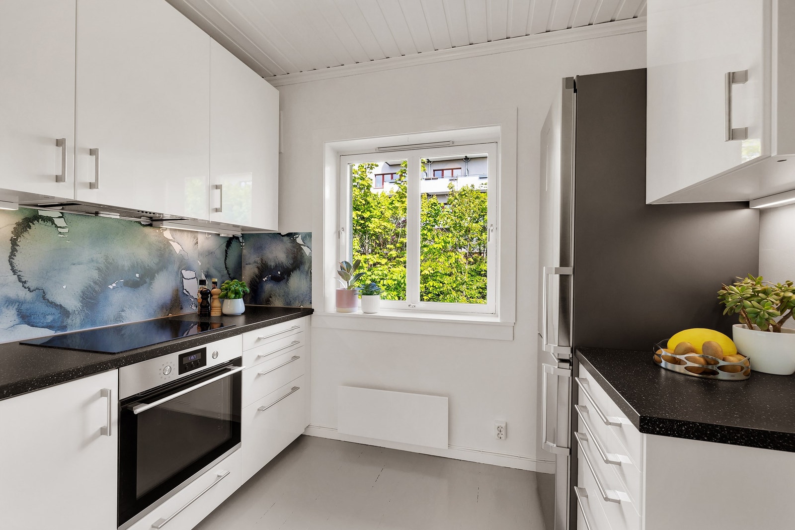 Praktisk separat kjøkken innredet med laminat benkeplate, nedfelt oppvaskkum med ett-greps armatur, laminerte plater på vegg mellom kjøkkenbenk og overskap. Galleribilde