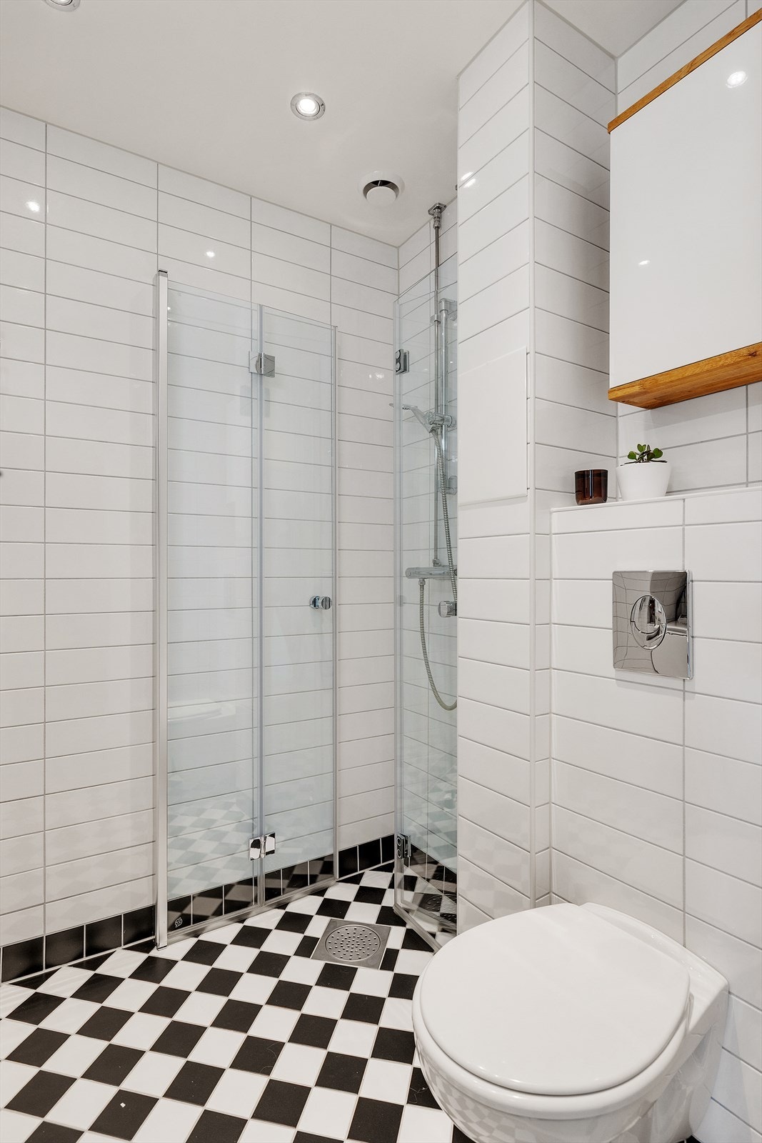 Badet er innredet med vegghengt servantskap, servant og ett-greps armatur, skap med speildør, belysning og stikkontakt over servant, dusjhjørne med innfellbare glassdører og dusjarmatur tilkoblet hånddusj samt vegghengt toalett. Galleribilde