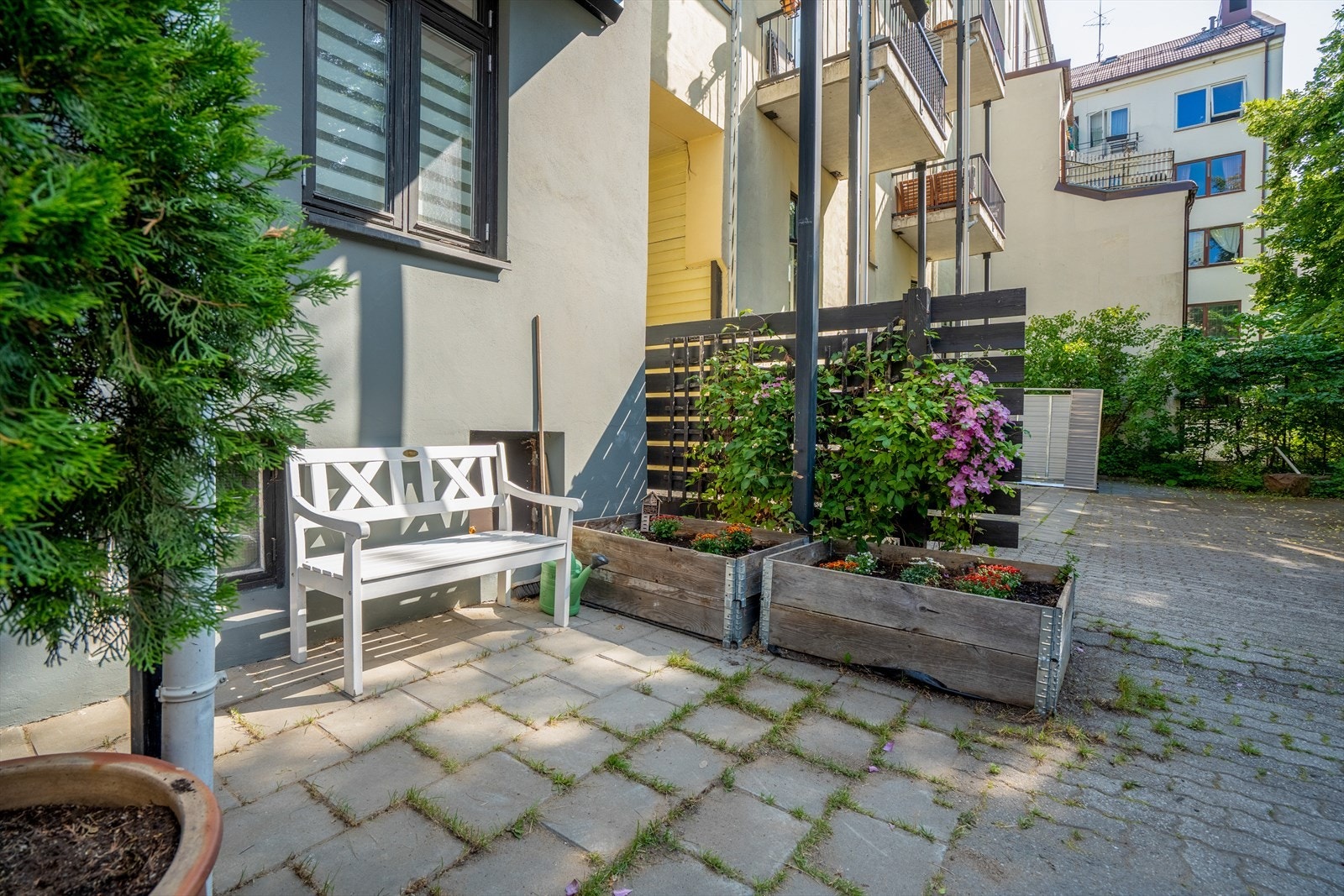 Bakgård med en koselig sittebenk og beplantning. Galleribilde