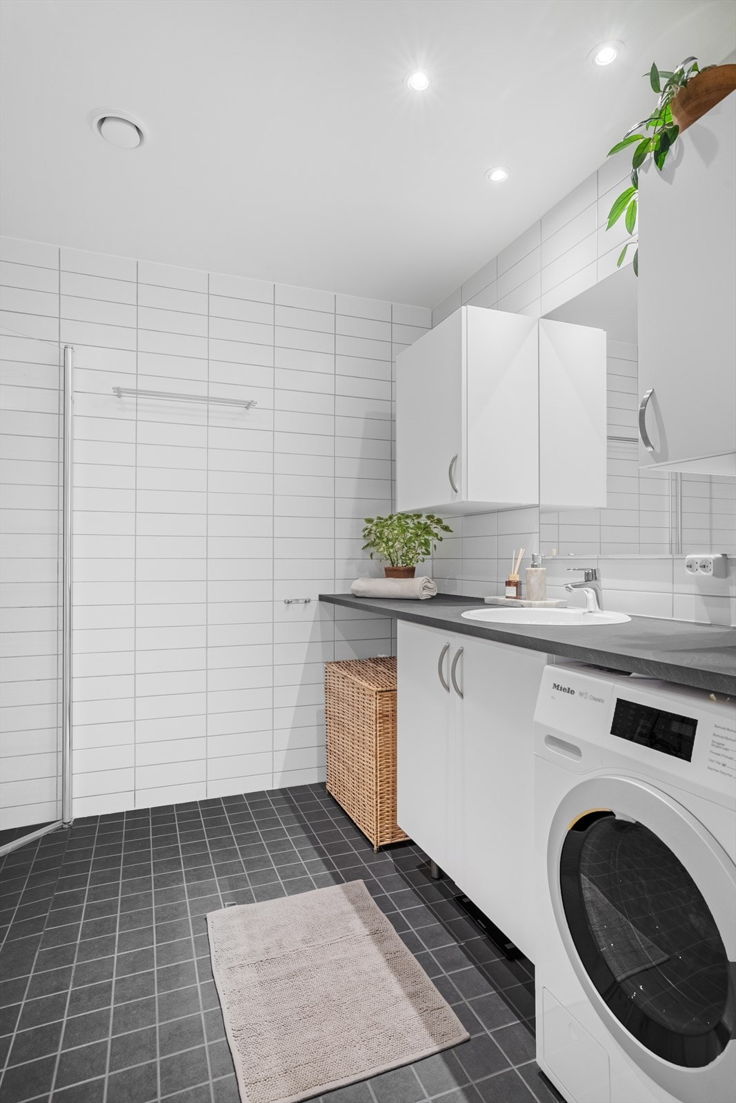 Badet er innredet med heldekkende benkeplate av laminat, opplegg til vaskemaskin, overskap og underskap og et vegghengt toalett. Galleribilde