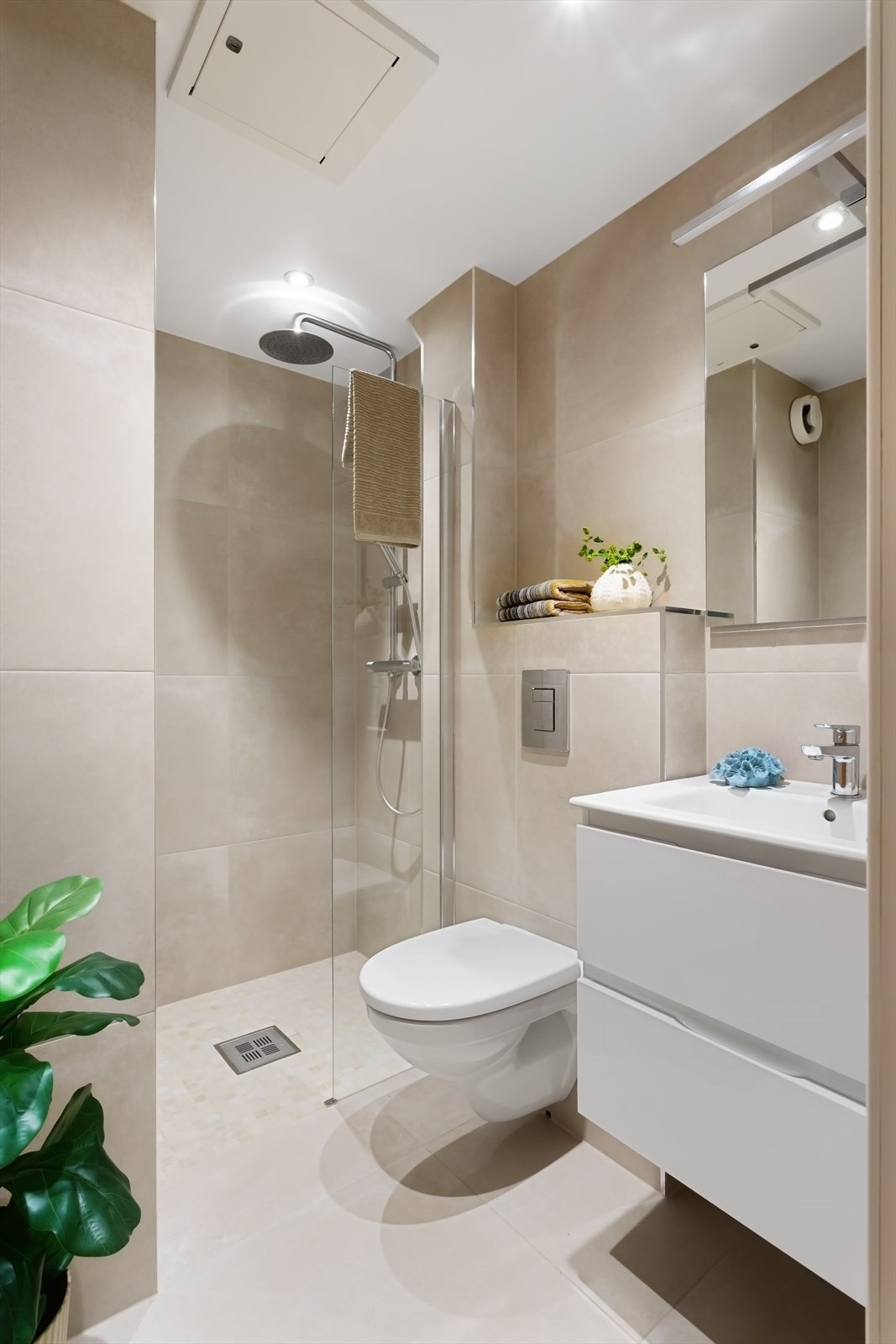 Pent flislagt bad med varmekabler pusset opp i 2023. Dusjnisje med regnfallarmatur, servant med skuffer, veggmontert toalett og downlights i himling. Galleribilde