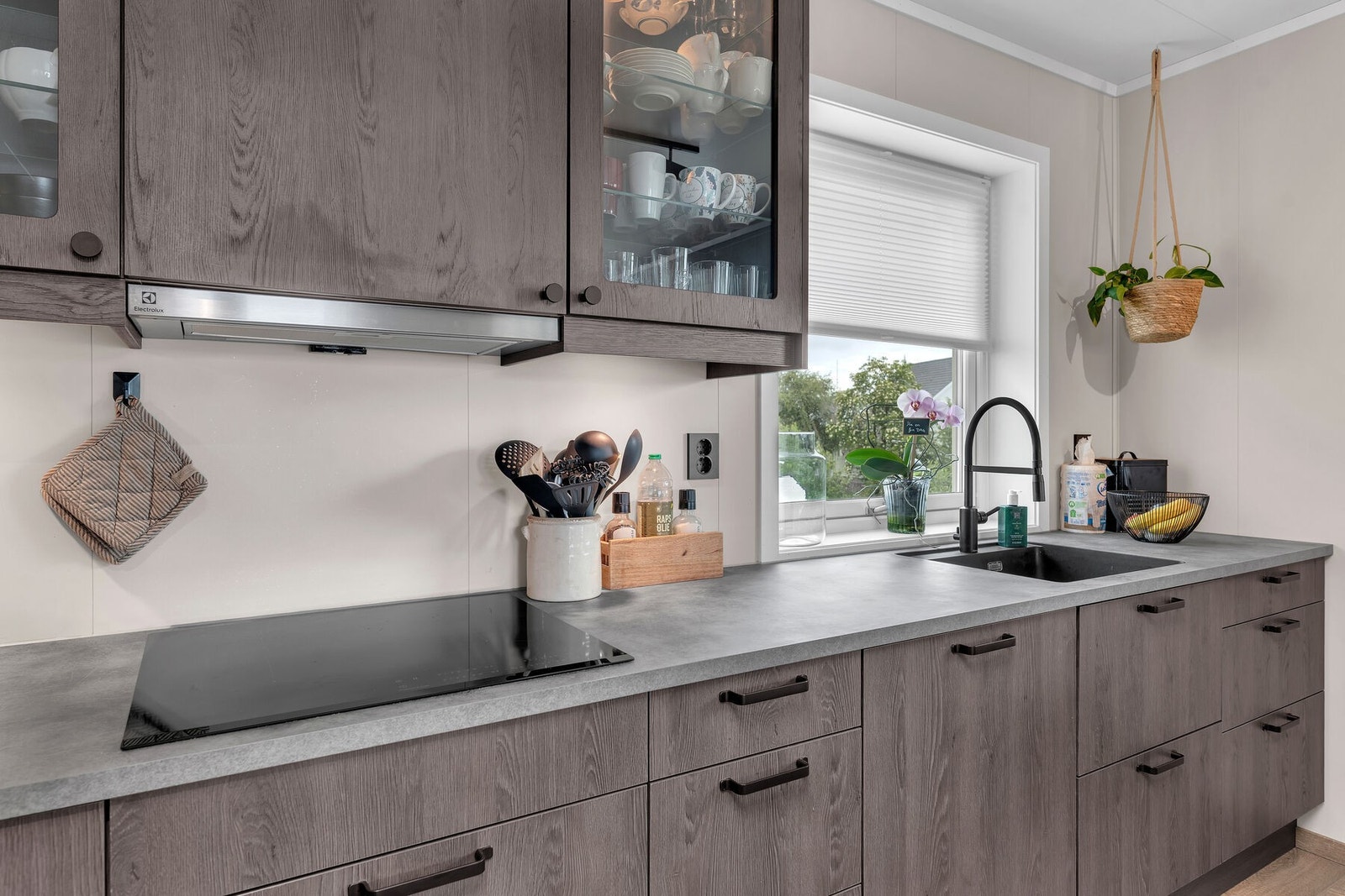 Tidsriktig kjøkkeninnredning i utførelse av mørk tre, som gir et eksklusivt preg. Galleribilde