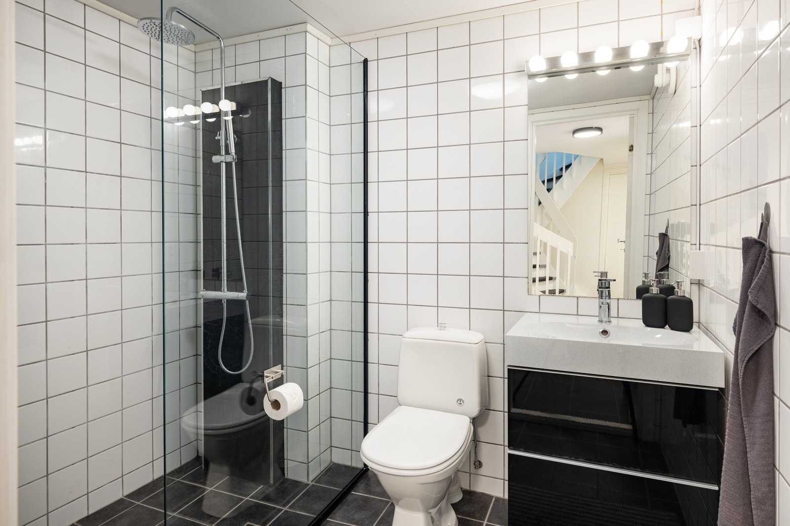 Badet har gulvmontert toalett, servant med underskap, regnfallsdusj og varmekabler i gulv. Galleribilde