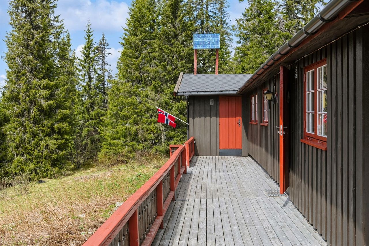 Terrassen strekker seg nesten på hele langsiden av fritidsboligen, og rundt hjørnet. I enden er det en dør inn til stuen. Galleribilde