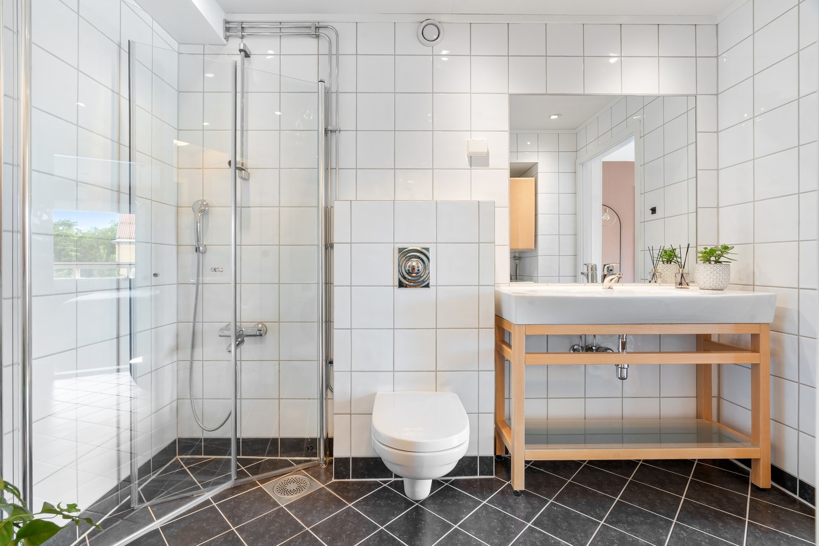 Badet er innredet med dusjhjørne, vegghengt toalett og servantseksjon med innfliset speil. Galleribilde