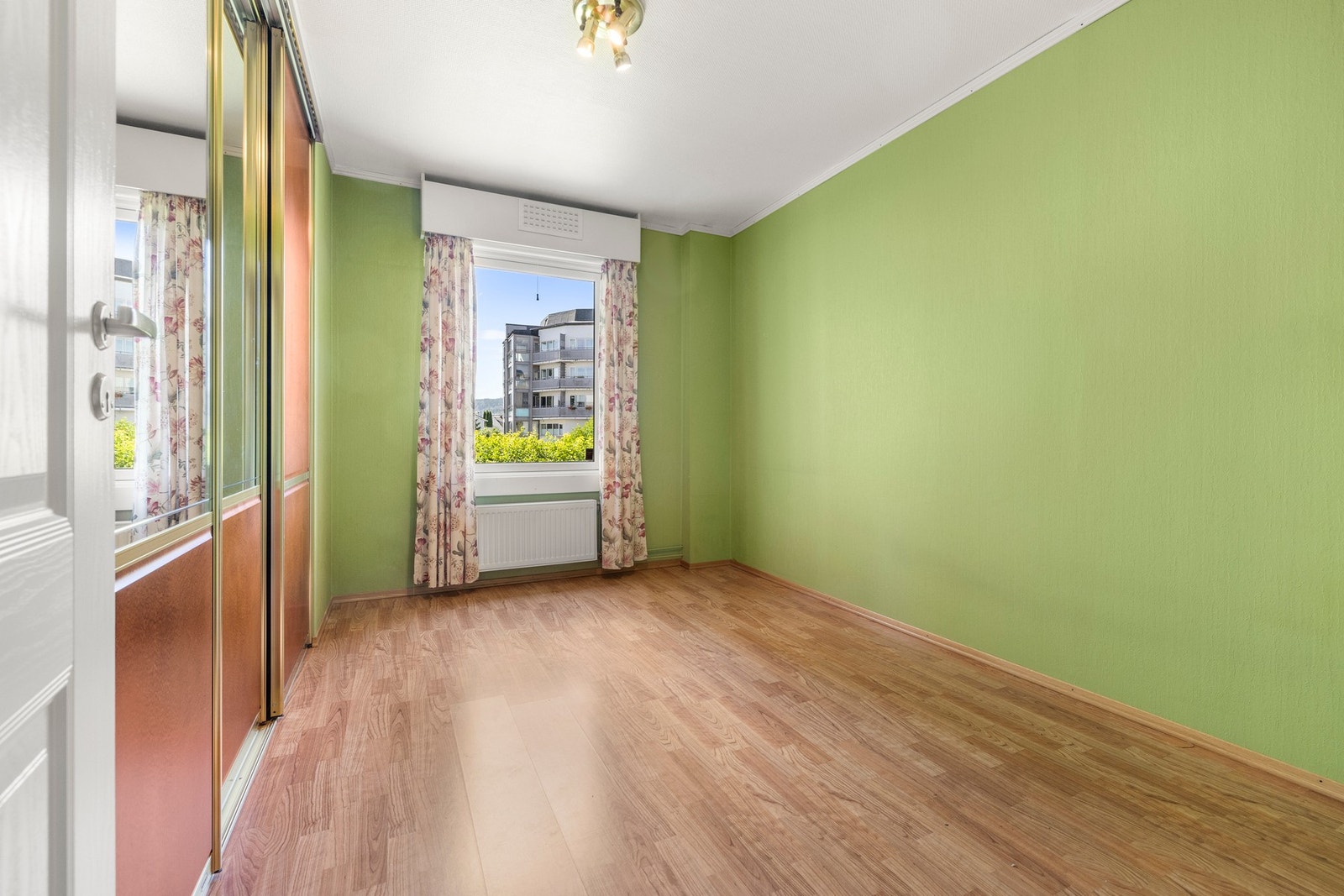 Soverom med rolig fargepalett og store vinduer. Innebygd garderobeskap gir god oppbevaring. Galleribilde