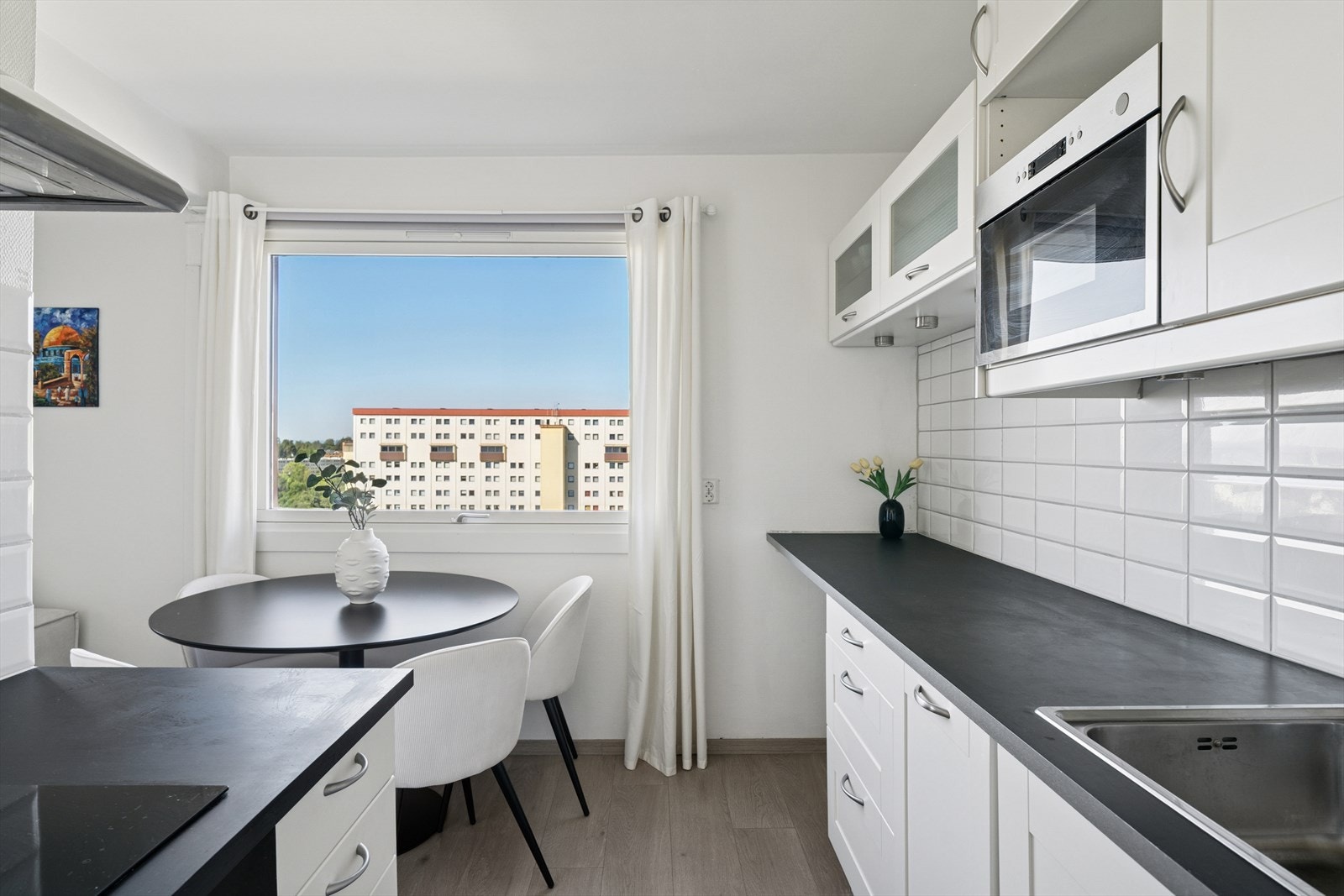 Det er fliser mellom benk og overskap, og belysning under overskapene. Hvitevarene består av integrert oppvaskmaskin, stekeovn og induksjonsplatetopp, mikrobølgeovn, samt frittstående kjøl/frys. Galleribilde