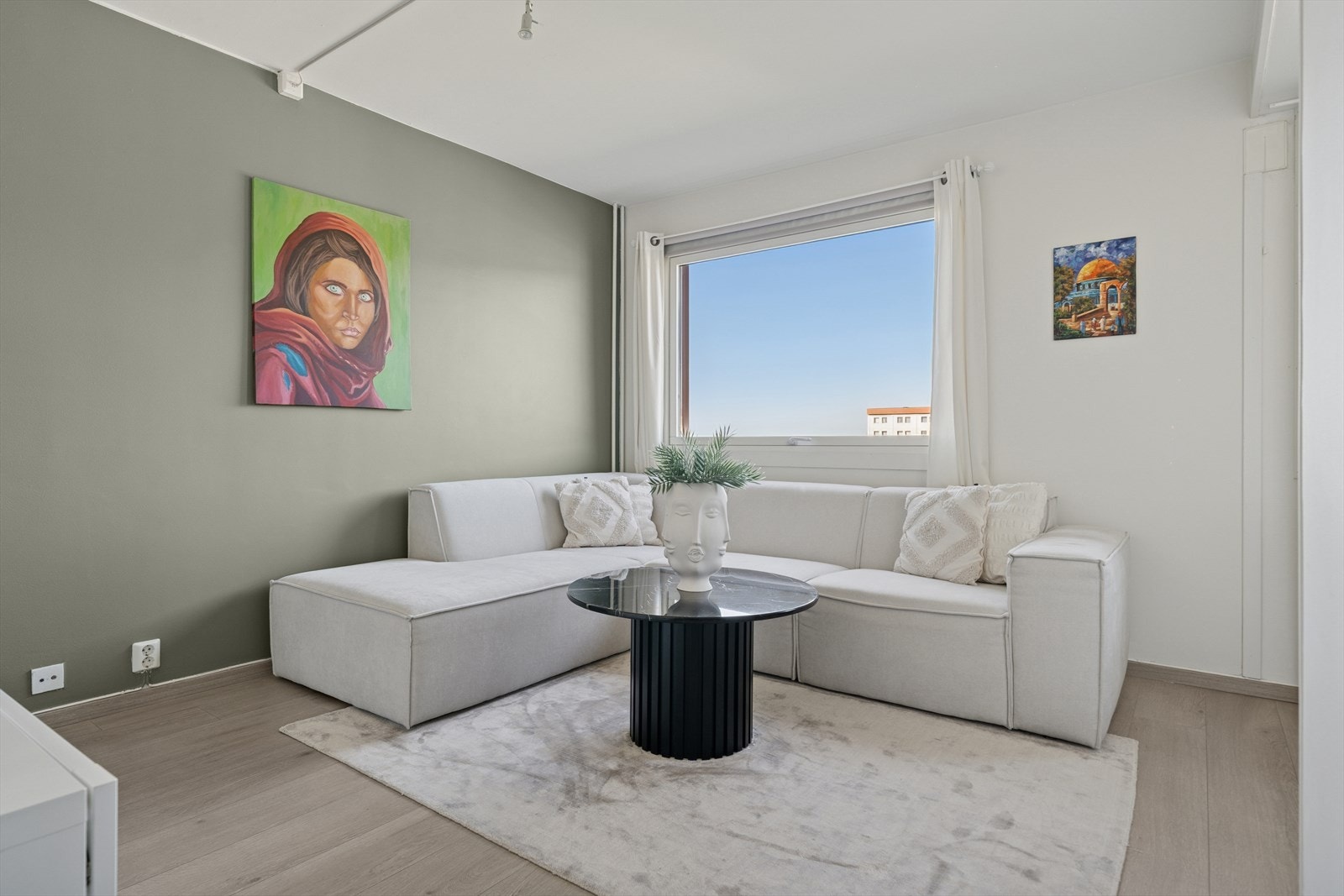 Lys og behagelig fargepalett gir rommet et stilrent og balansert uttrykk, mens utsikten fra stuen bidrar til en åpen og luftig atmosfære. Galleribilde