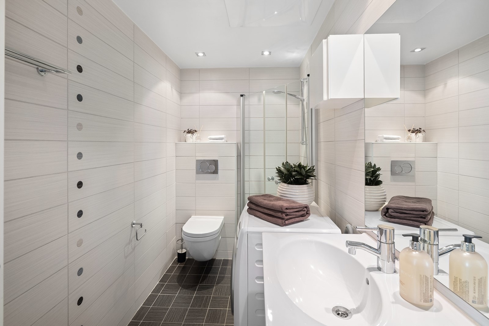 Utstyrt med dusjhjørne, innfellbare dusjdører, opplegg for vaskemaskin, stoppekran og veggmontert wc Galleribilde