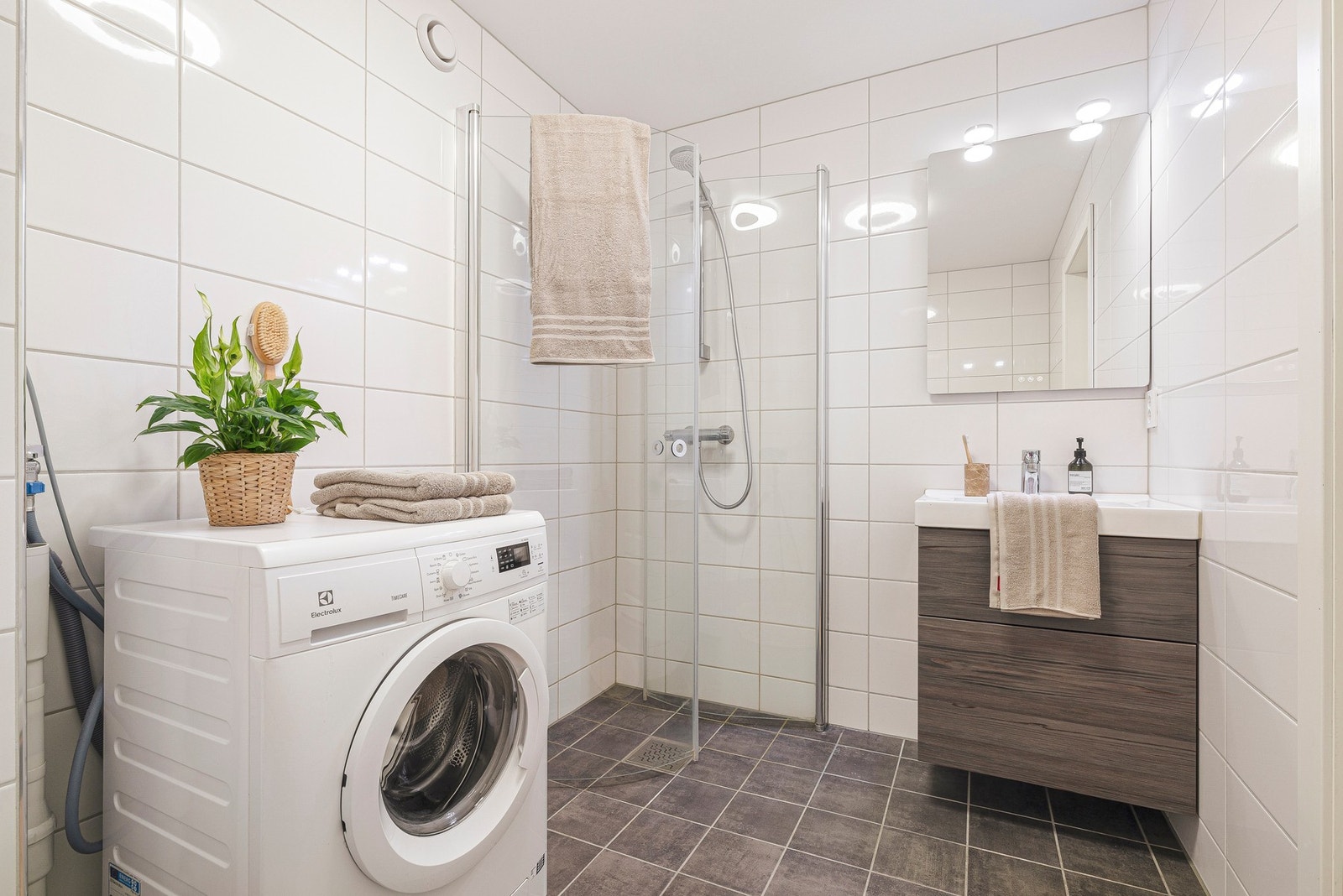 Rommet inneholder vegghengt toalett, servantmøblement, speil og dusjhjørne Galleribilde