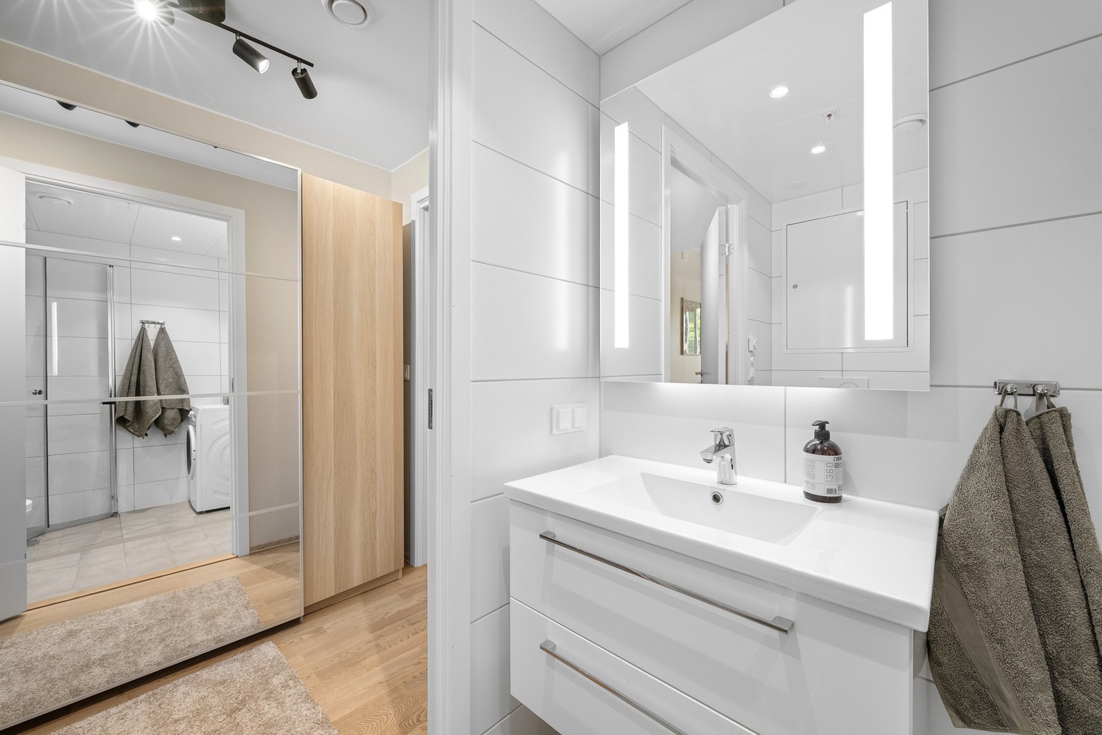 Badet er innredet med moderne baderomsinnredning, vegghengt toalett, og dusjhjørne med innfellbare dører. Galleribilde