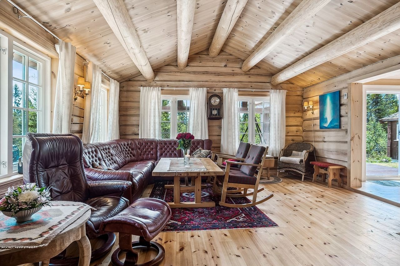 Stuen er hyttas samlingspunkt og har en vedovn som gir god varme. En smart løsning med takventil og kanalvifte fordeler varmluften fra stuen videre til mellomgangen ved kjøkkenet og soverommene. Galleribilde