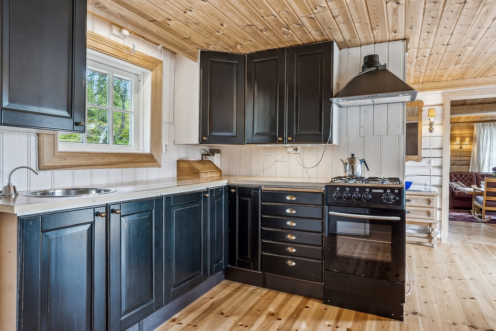 Kjøkkenet har en praktisk innredning med malte, profilerte fronter og laminatbenkeplate. Innredningen består av overskap, underskap og skuffer. Det er utstyrt med en propankomfyr og en nedfelt vask med avløp for gråvann. Galleribilde