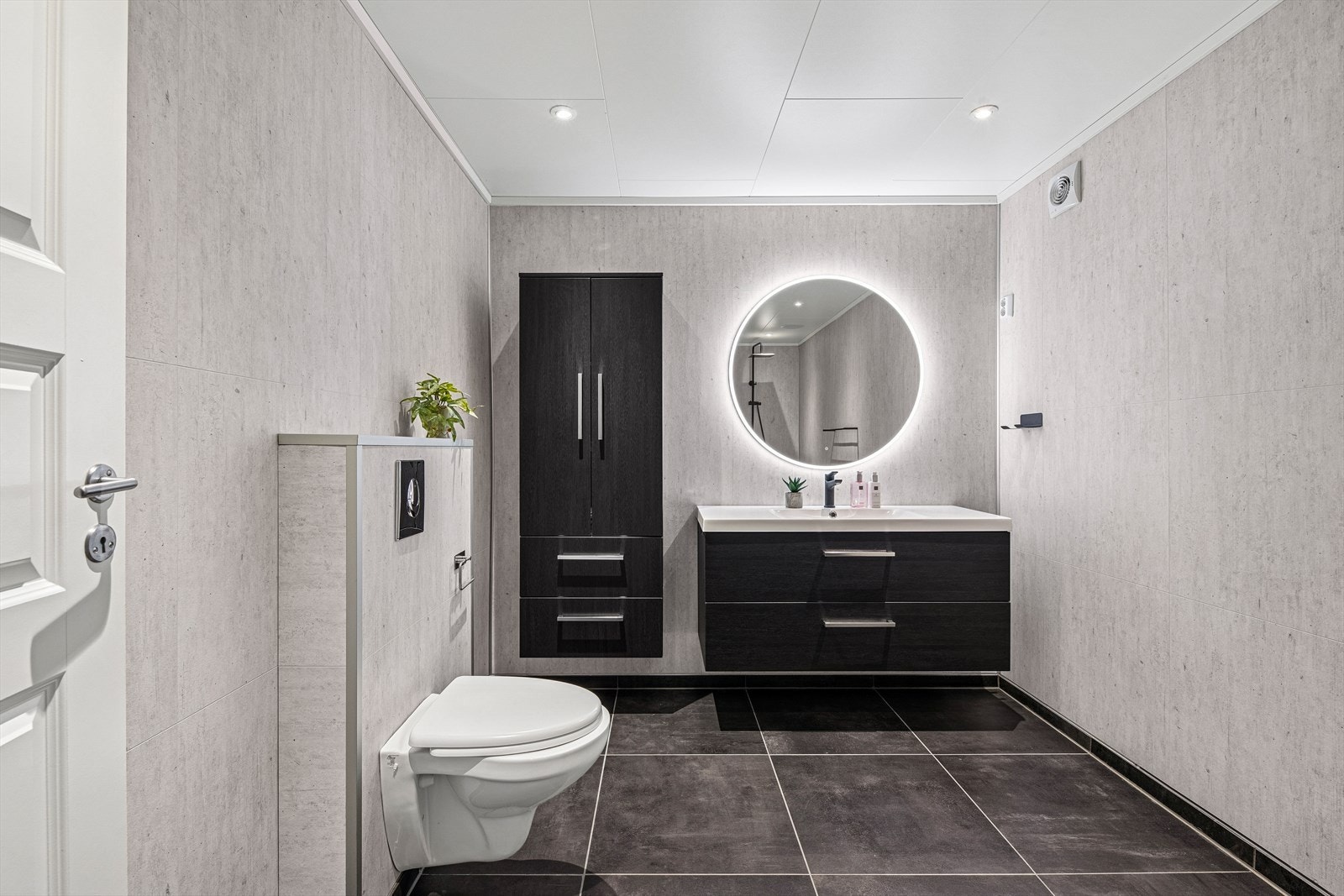 Badet har en flott innredning med nedfelt servant, sort ettgreps blandebatteri, speil med lys og veggmontert toalett. 60x160 høyskap. Galleribilde