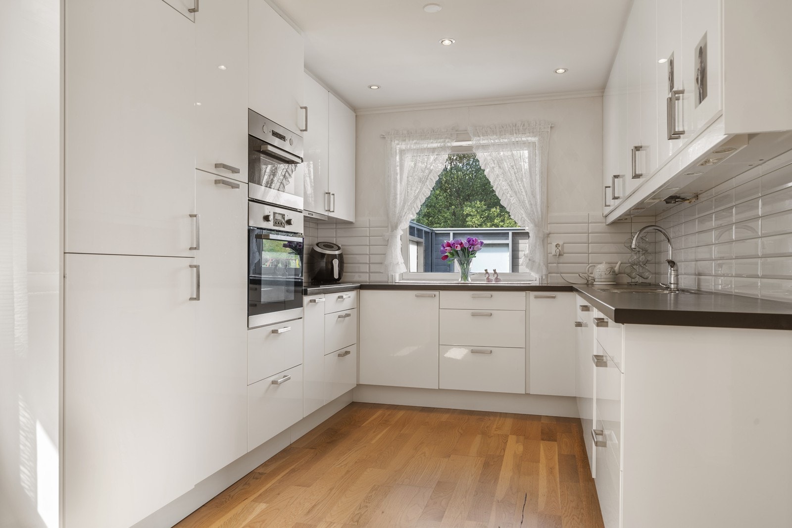 Kjøkkenet har spiseplass, fin høyglanset og hvit innredning samt integrerte hvitevarer. Galleribilde