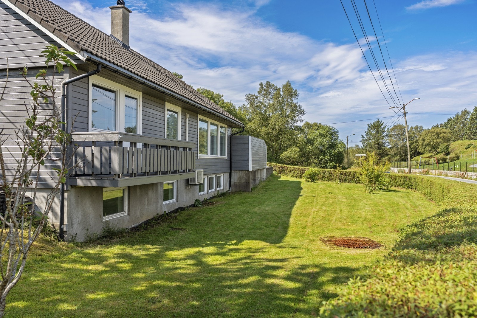 Pent opparbeidet tomt med asfaltert gårdsrom og plen med diverse beplantning. Galleribilde