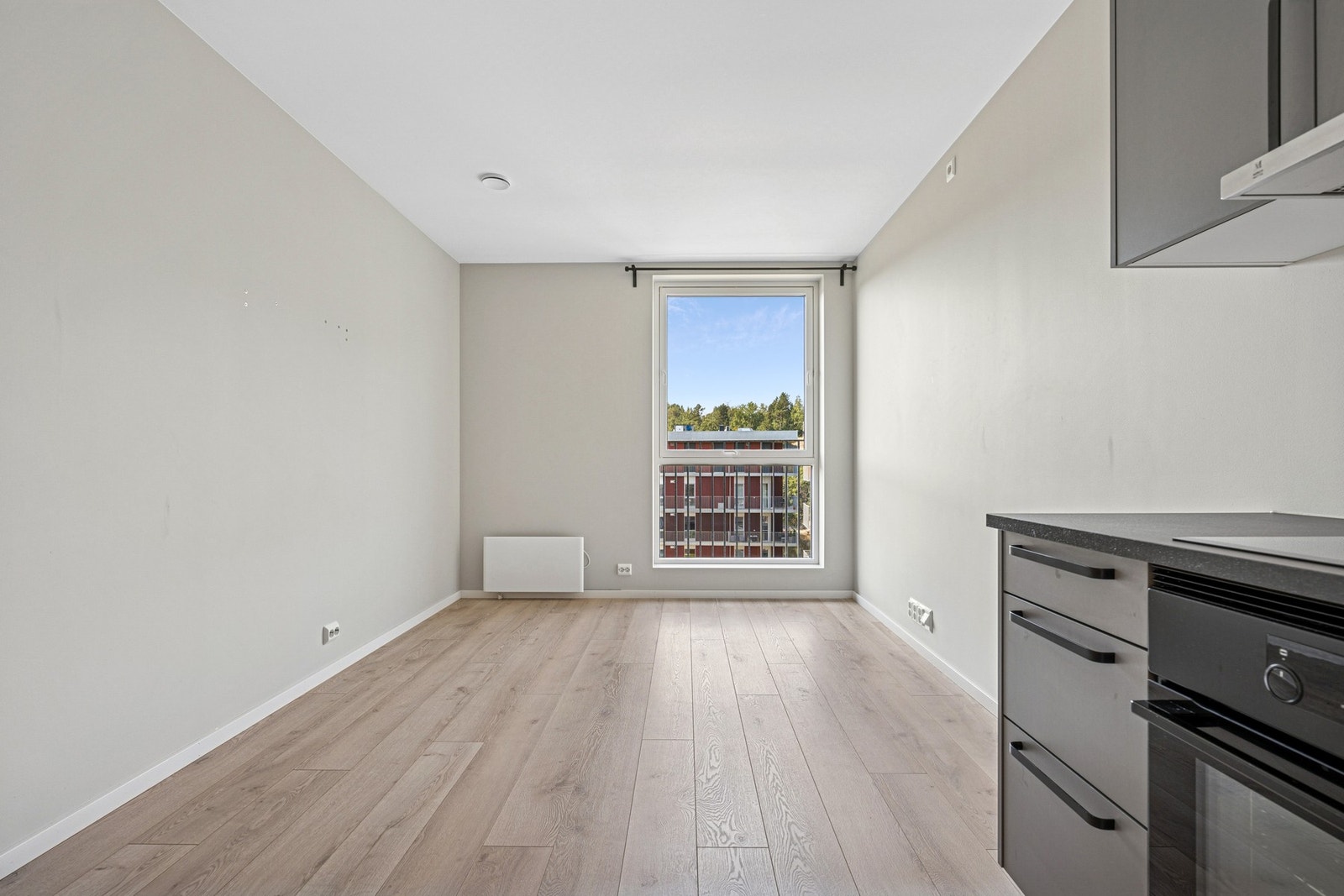 Lys og trivelig stuesone med store vindusflater og utsikt mot grøntområder. Fin plass til både sofakrok og et lite spisebord. Galleribilde