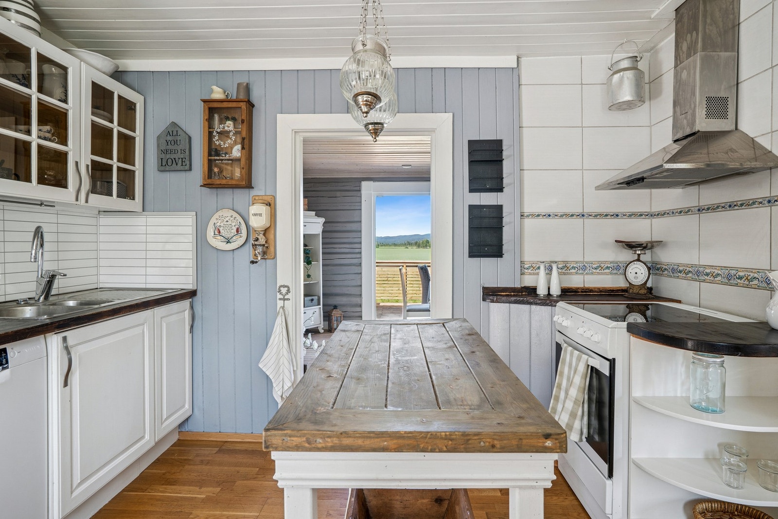 Kjøkkeninnredning med profilerte fronter fra ukjent årstall. Benkeplater av tre. Nedsenket oppvaskkum
med ett-greps armatur. Plater mellom benkeplate og overskap. Stikkontakter under overskap. Galleribilde