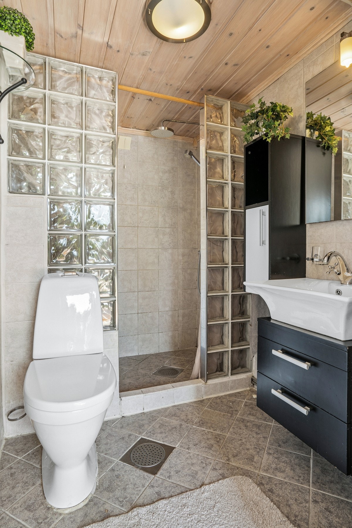 Baderom fra ukjent årstall. Flislagt gulv med varme og flislagte vegger. Badet har dusjnisje, baderomsinnredning og toalett. Galleribilde