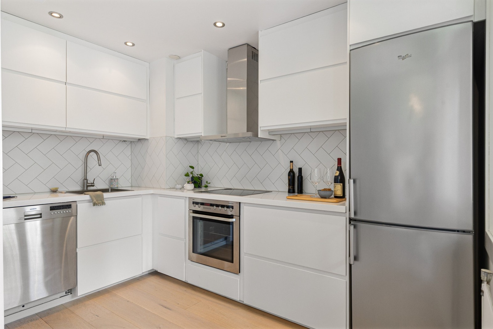 Praktisk kjøkken med integrerte hvitevarer og tidløse, glatte fronter. Galleribilde