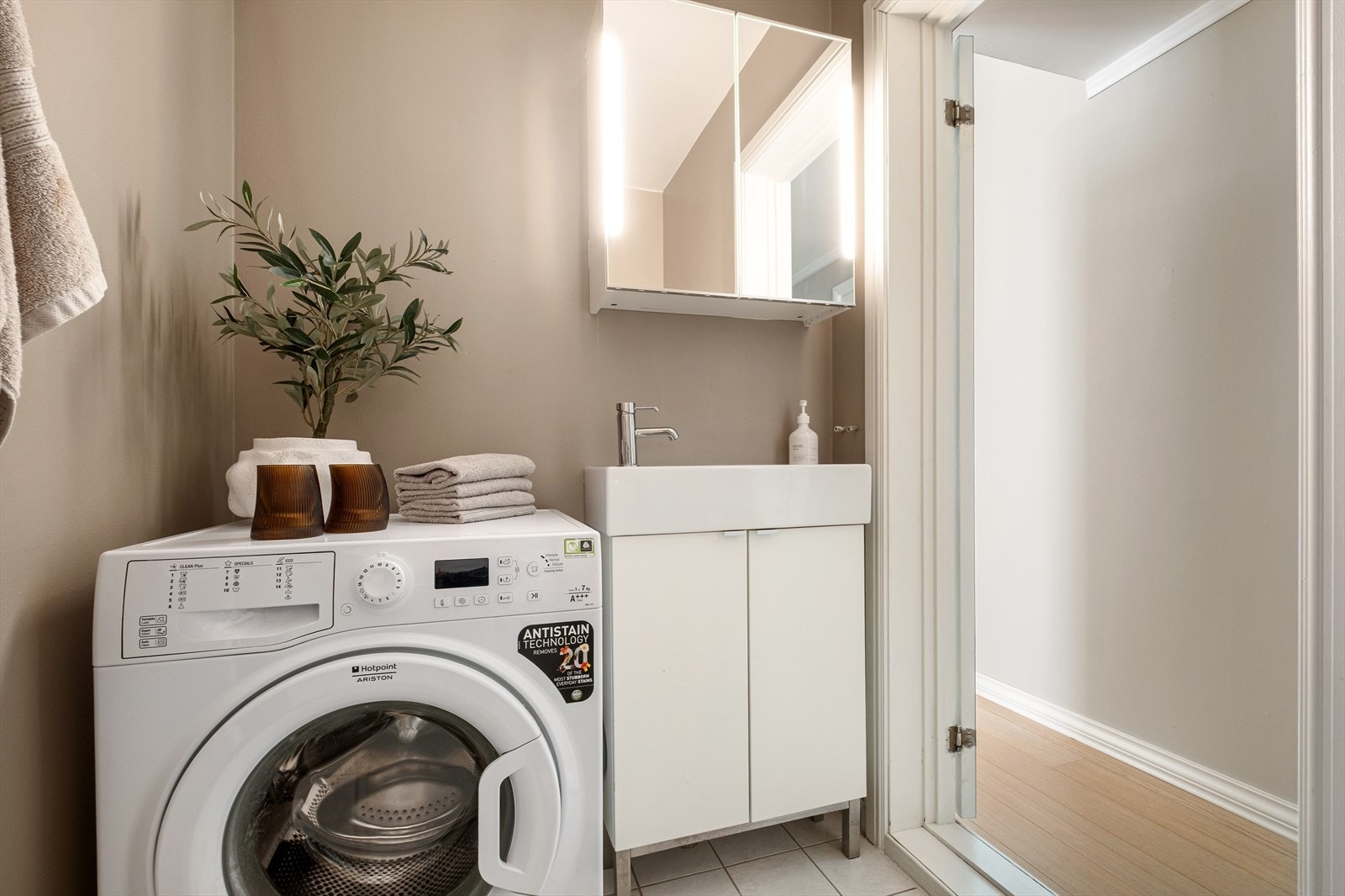 Badet er utstyrt med servantinnredning, enkelservant med ett-greps armatur, dusj med svingbare dører, speilskap, frittstående toalett, vaskemaskin Galleribilde