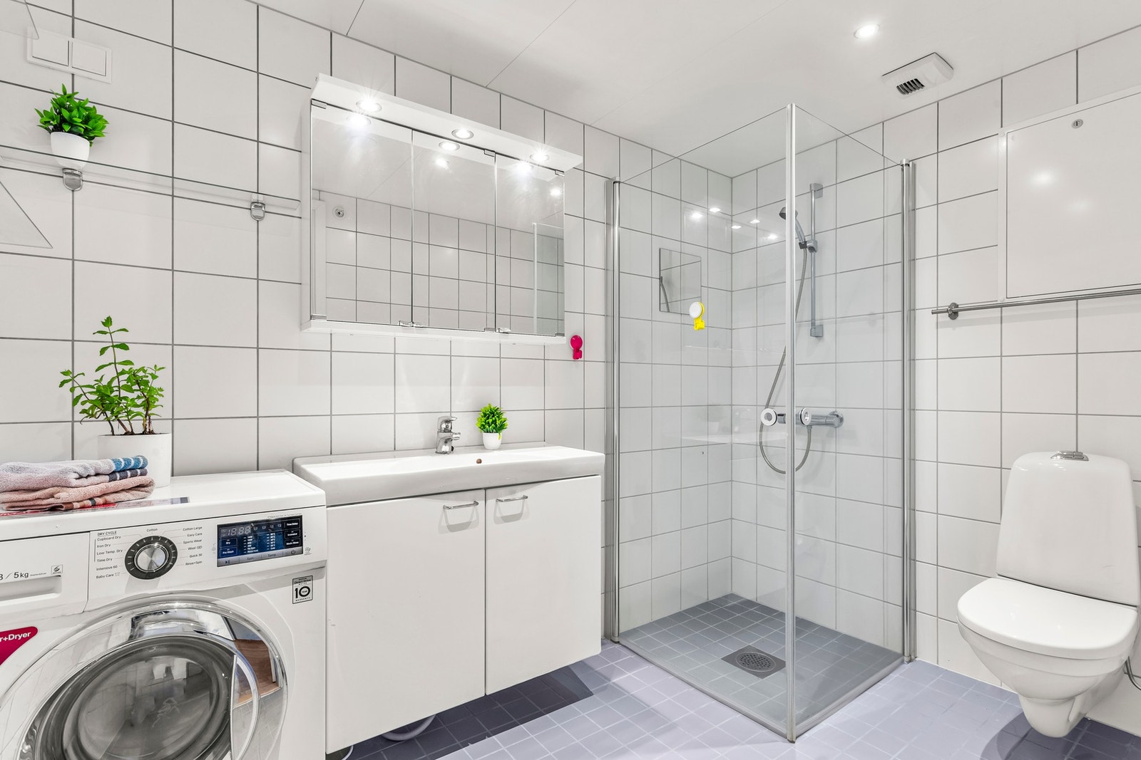 Leiligheten har et romslig og tidløst bad, med vegghengt toalett og nedsenket dusjhjørne, med innfellbare dører i glass. Galleribilde