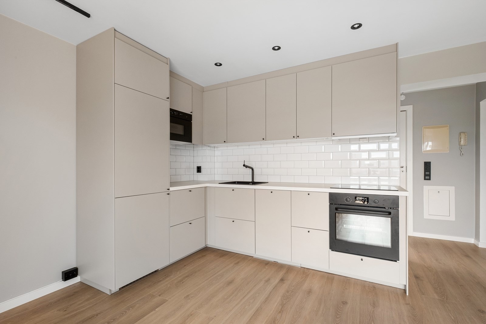 Kjøkkenet ligger i en åpen løsning mot stue og skaper en sosial atmosfære. Kjøkkeninnredning består av glatte, beige fronter og benkeplate av laminat med nedfelt vaskekum. Galleribilde