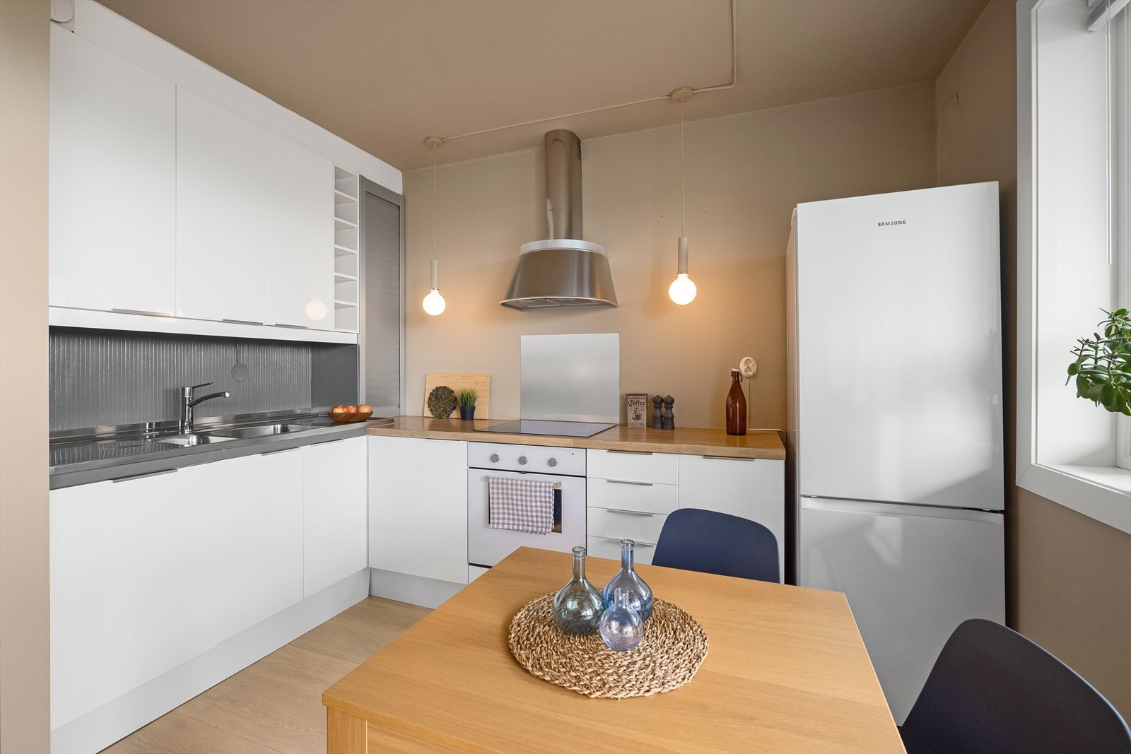 Kjøkkeninnredningen fra Ikea består at glatte, lyse fronter og en pen benkeplate i laminat med dobbel kum med benkebeslag. Galleribilde