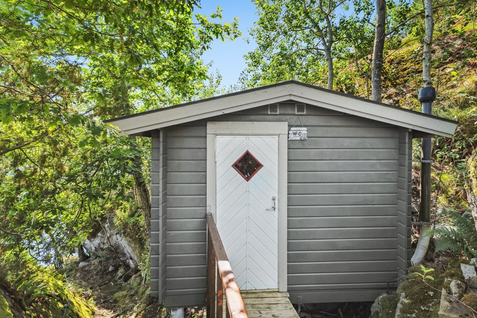 Toalettløsningen er i eget bygg. Bygget står på søyler direkte på fjell, med vegger i reisverk og liggende dobbelfalset kledning. Taket er et tradisjonelt saltak tekket med papp Galleribilde