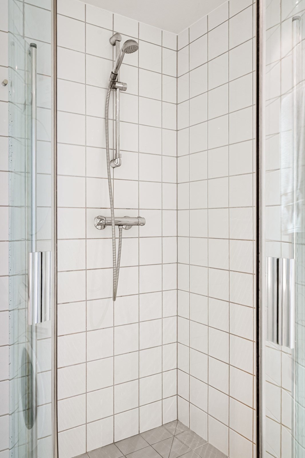 Dusjhjørne med glassdører og dusjbatteri i rustfritt stål fra Hans Grohe. Galleribilde