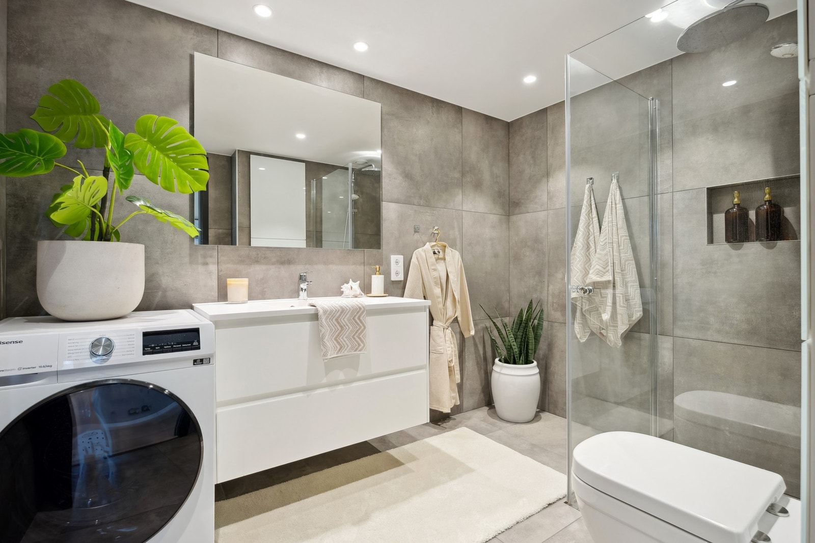 Badet i leiligheten er smakfullt flislagt med mørke, nøytrale toner som gir et rent og tidsriktig uttrykk. Galleribilde