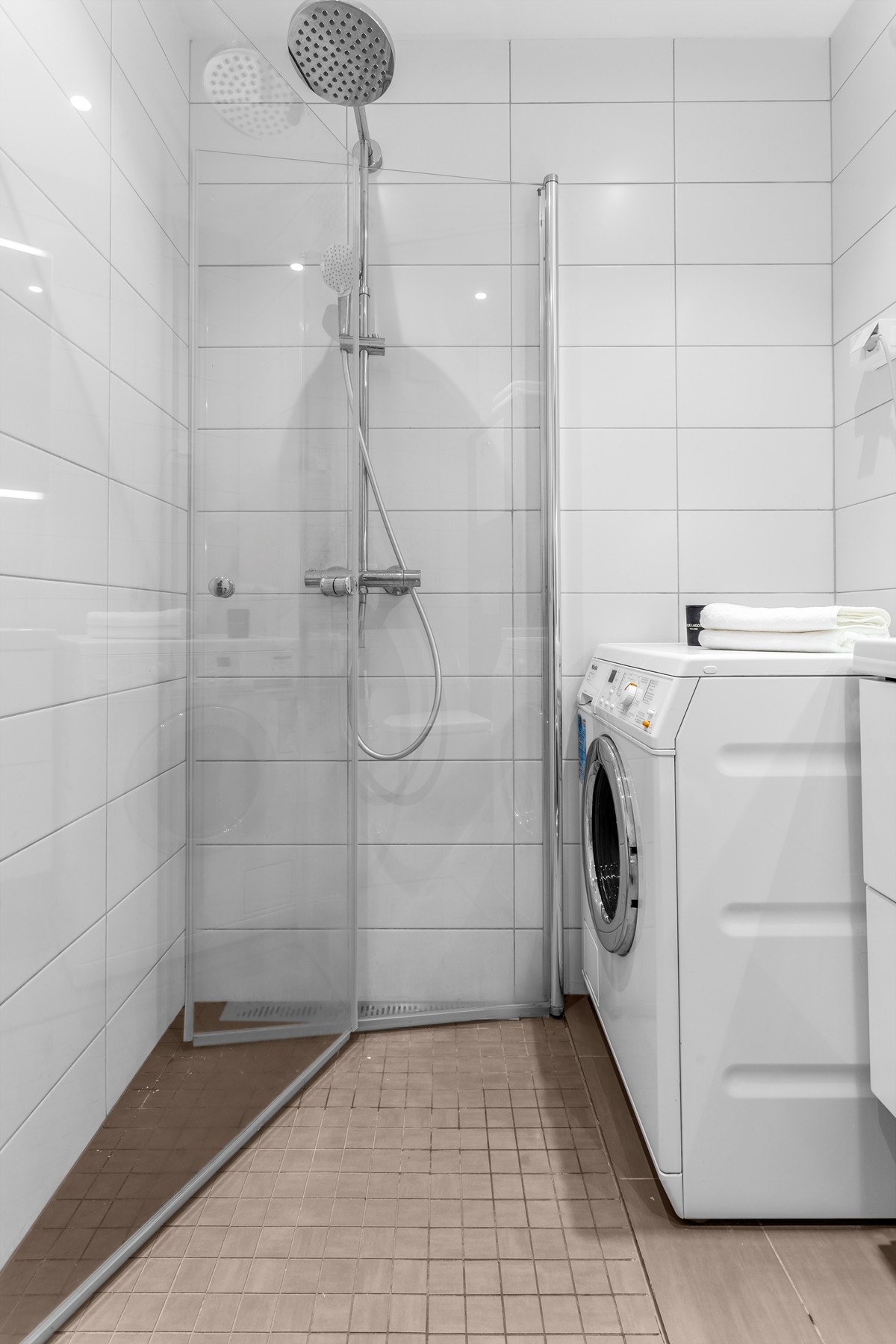 Baderommet har dusjhjørne med regnfallsdusj, servant med glatte fronter, vegghengt toalett og opplegg for vaskemaskin Galleribilde