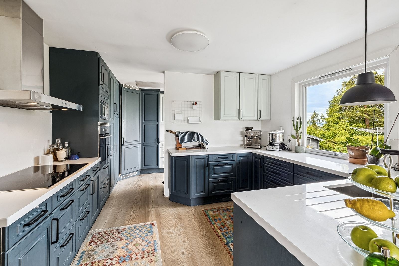 Innholdsrikt kjøkken med masse skap- og benkeplass, med kjølerom i hjørnet. Galleribilde