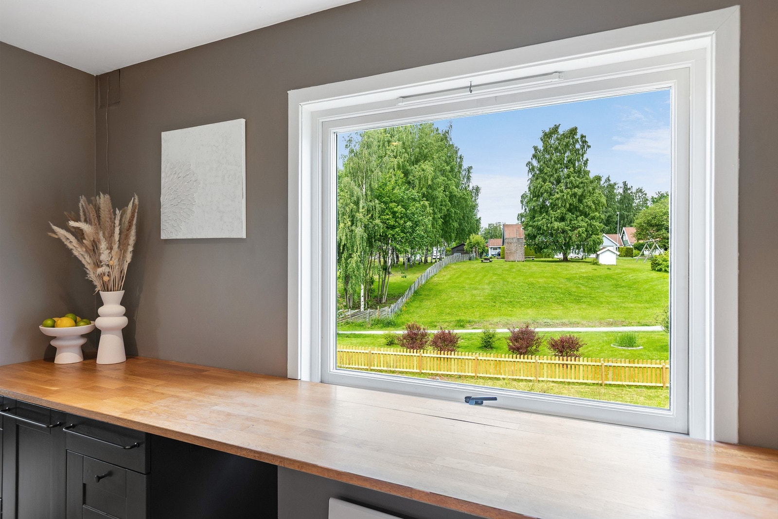 Hyggelig utsyn fra kjøkkenet og ut mot friareal. Tomten er også dels inngjerdet med stakittgjerde. Galleribilde