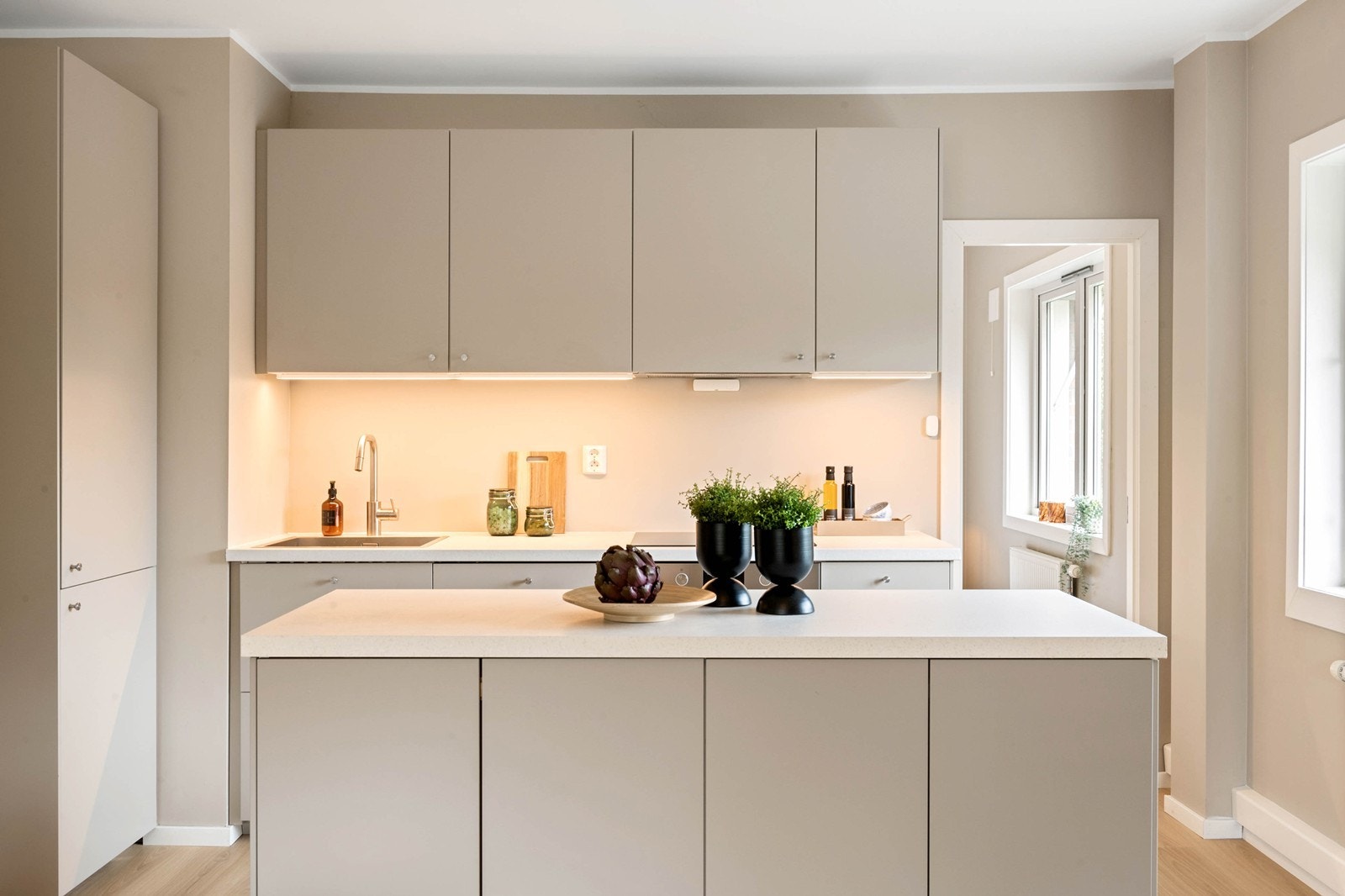 Kjøkkeninnredning bestående av bl.a. laminat benkeplate, kjøl/fryseskap, oppvaskmaskin, platetopp, stekeovn, vannstoppsystem og komfyrvakt. Galleribilde